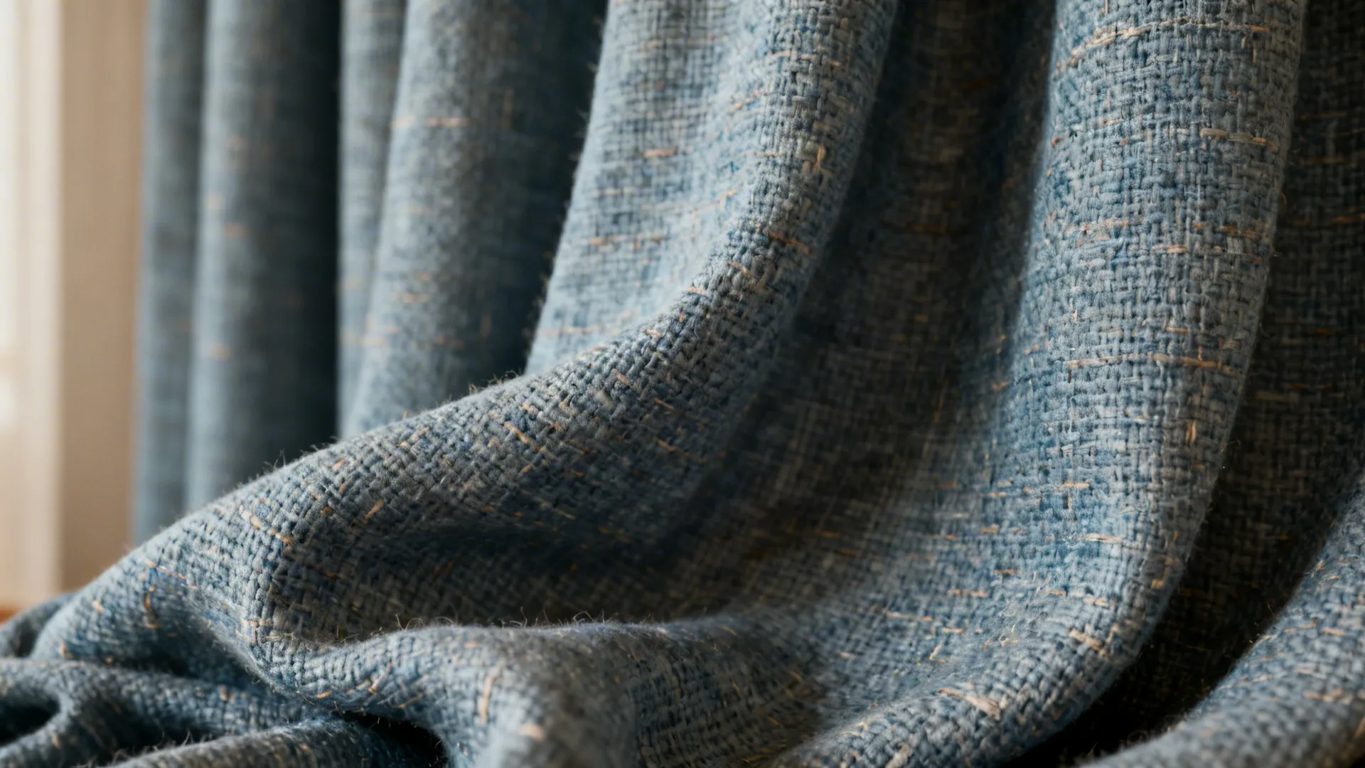Close-up of a woven linen-blend blue-grey curtain showing texture and weave.