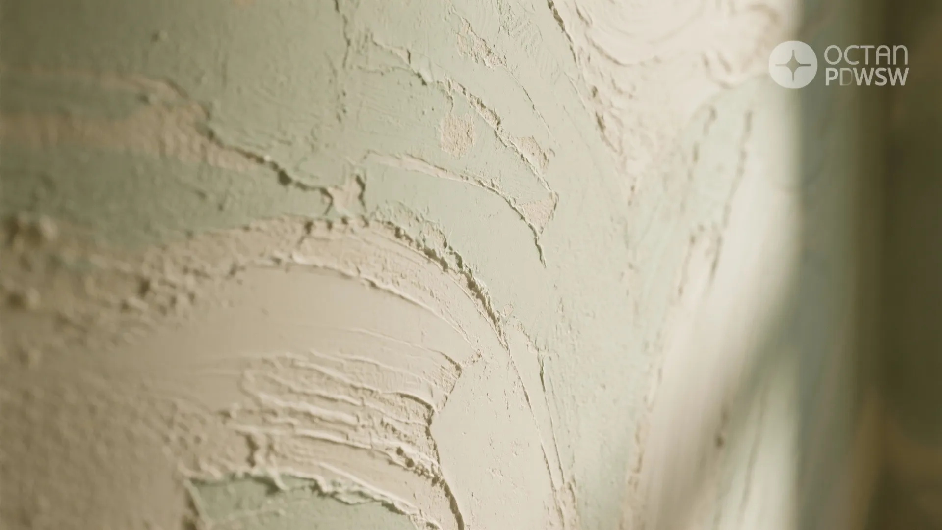 Close up view of light green wall panel showing thick white textured paint brush strokes detail