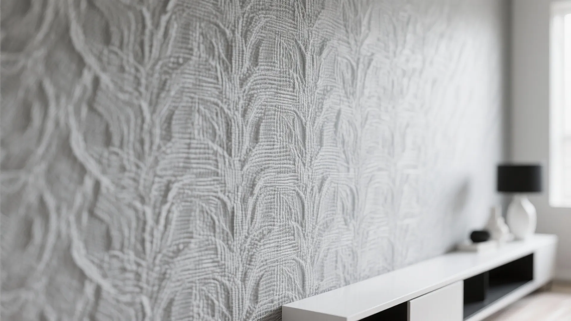 Close up view of grey textured wall paper with leaf patterns behind white storage cabinet
