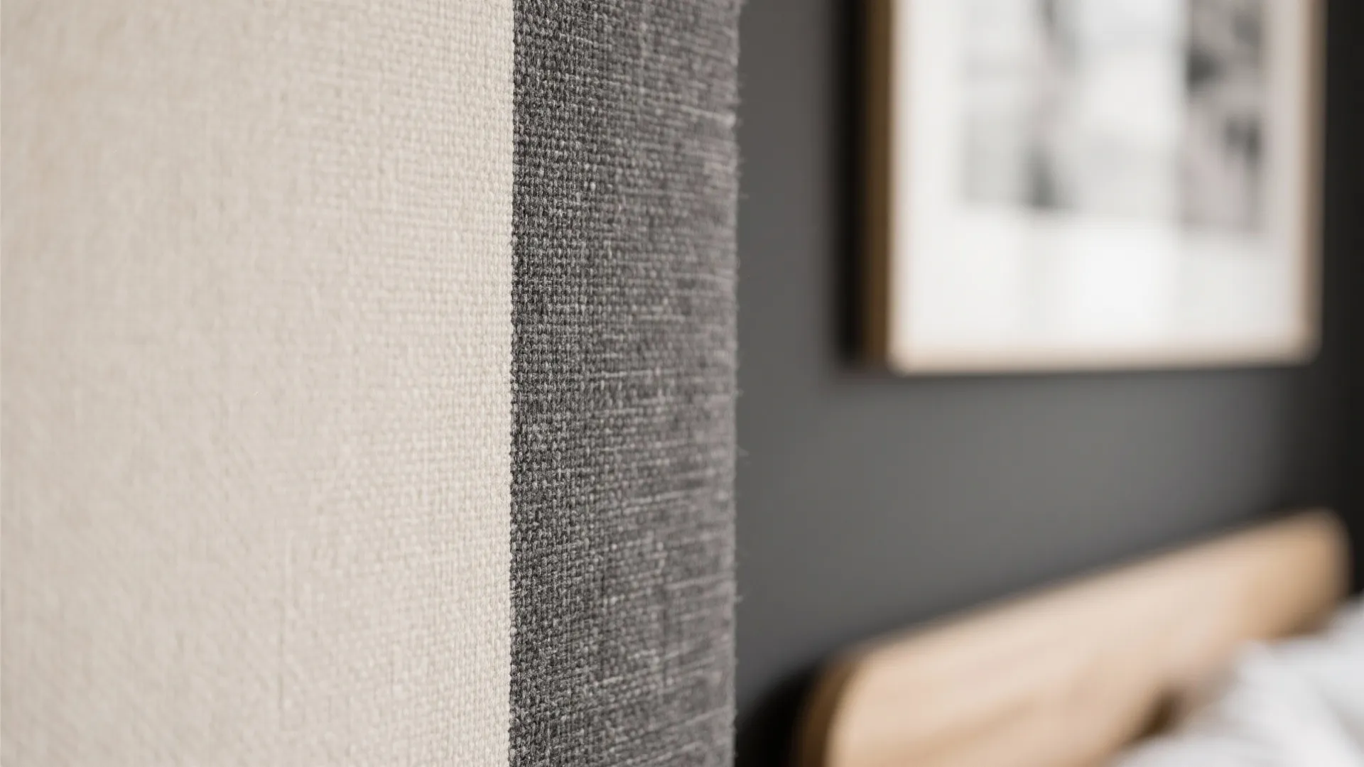 Close up of beige and grey woven fabric texture with blurred bedroom background and bed
