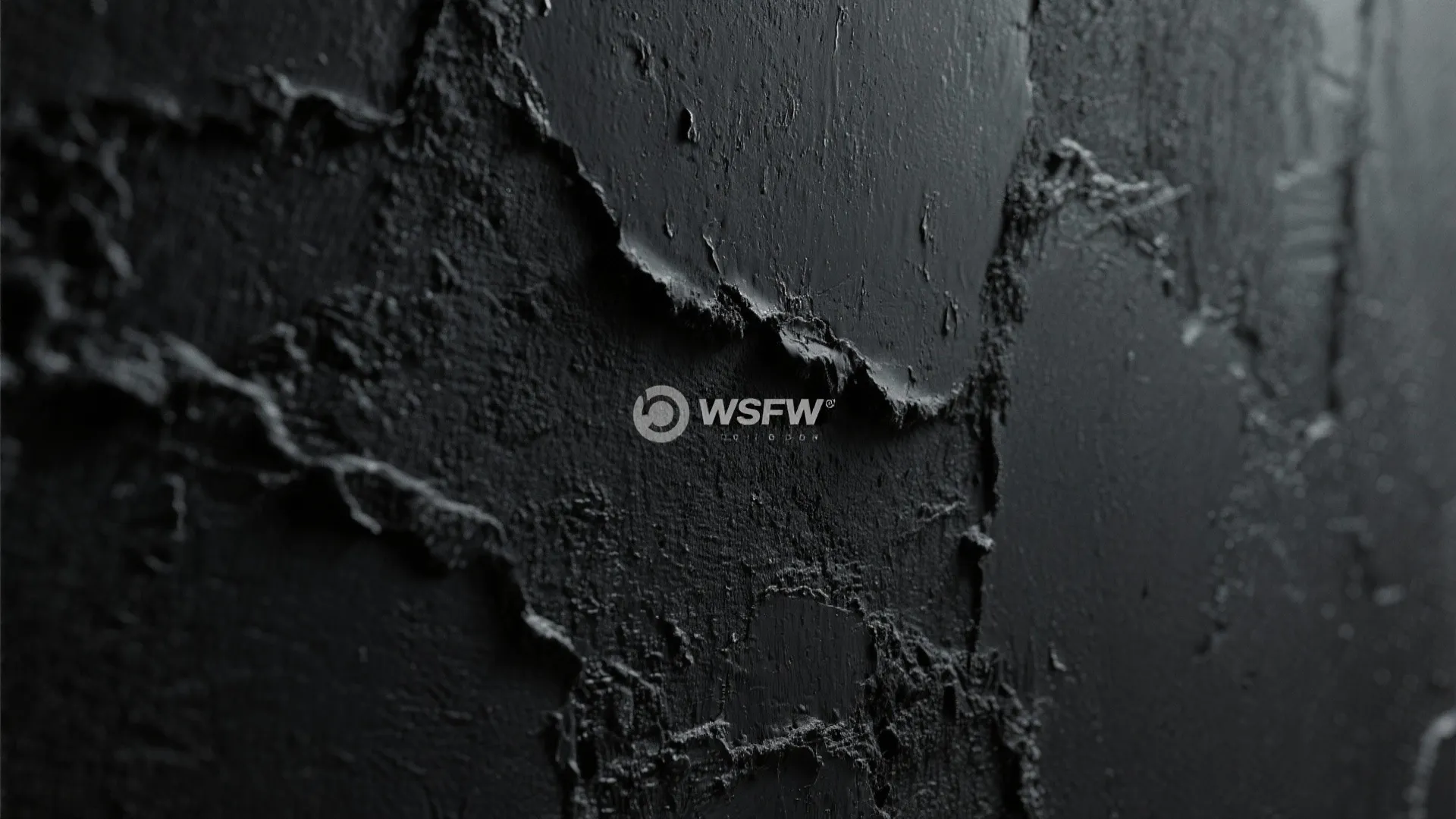 Close up of a black textured wall panel showing rough matte surface and unique artistic details