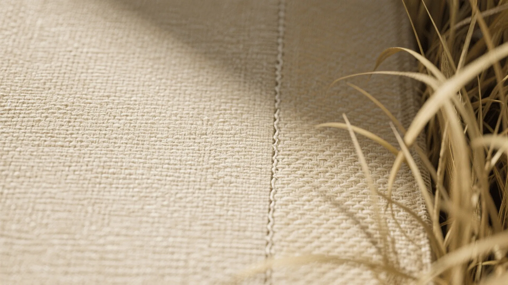 Close-up of linen-effect wallpaper showing warm beige grasscloth texture and natural fibers.