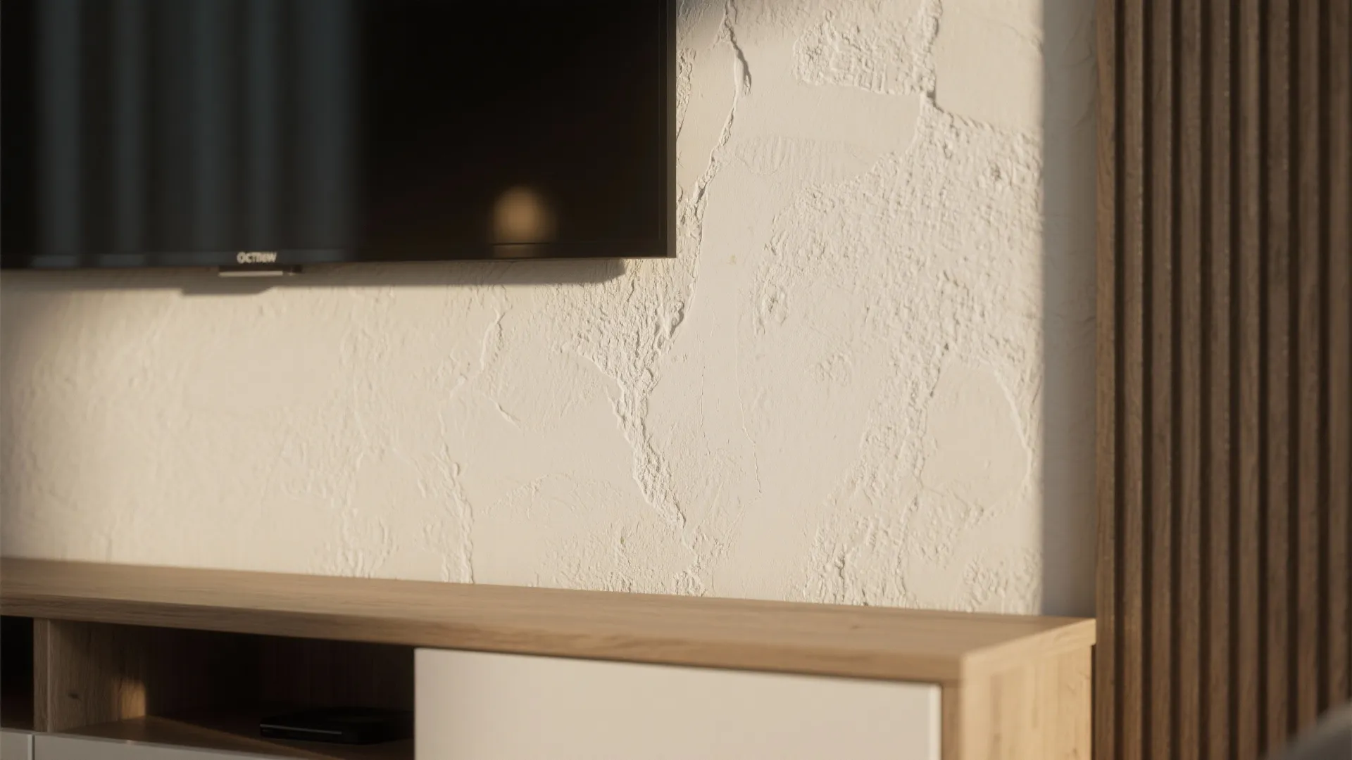 Close up of a white textured wall behind a television and a wooden storage cabinet