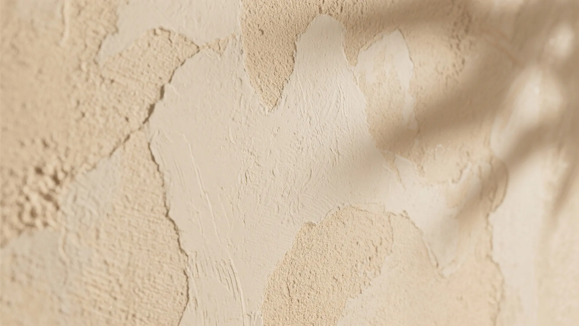 Close up view of a textured sand colored wall with soft shadows and uneven surface details