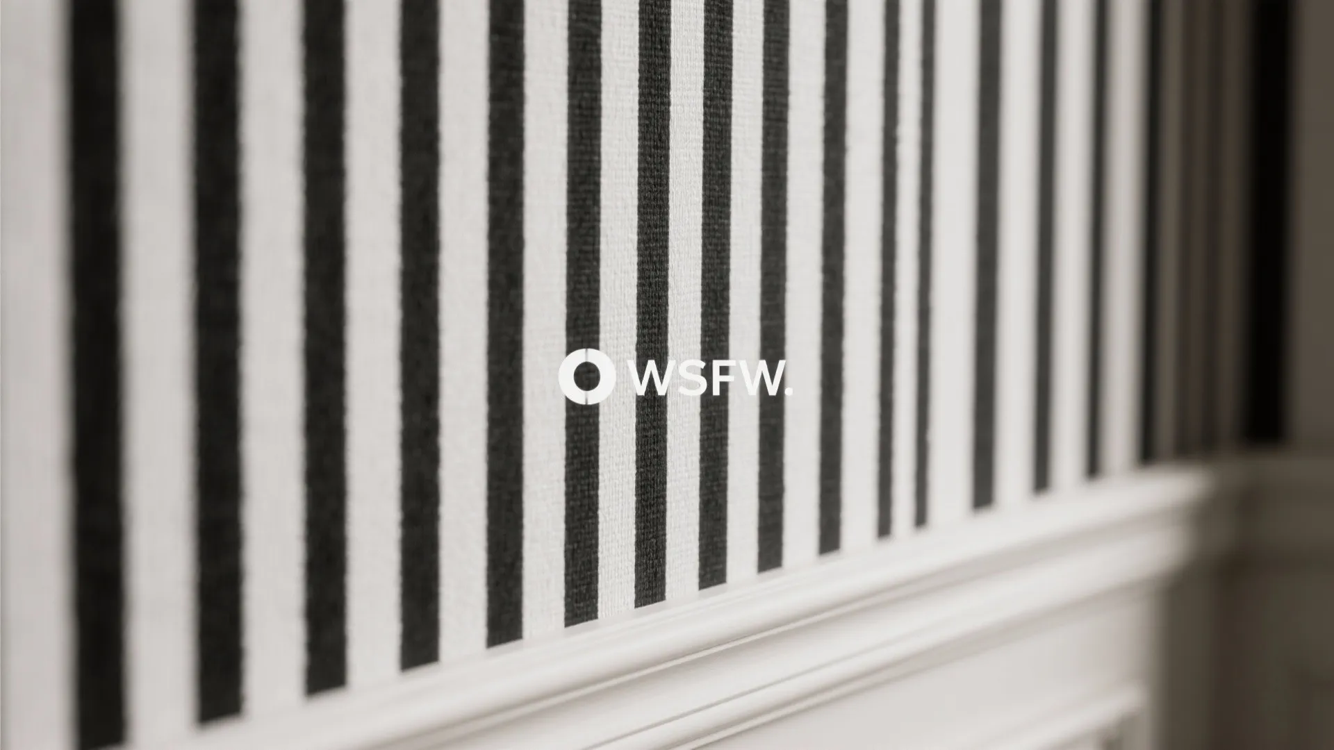 Close-up of subtle black-and-white striped textured wallpaper showing fabric-like finish