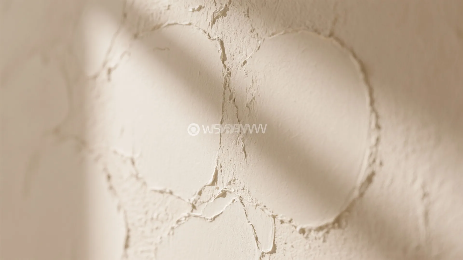 Cream textured wall with circular patterns made of wall putty and soft sunlight shadow details