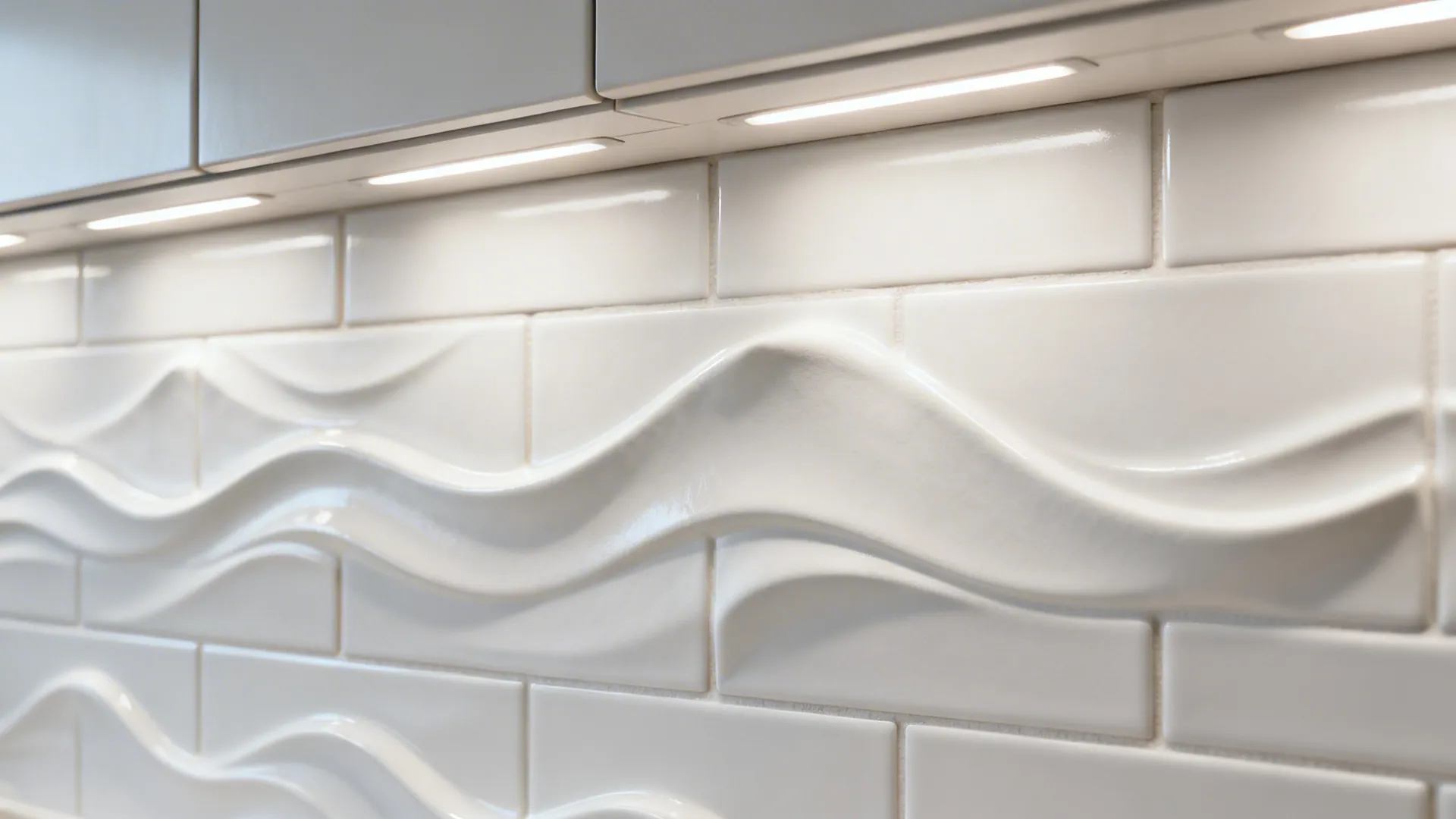 Macro of white 3D relief tiles with subtle wave texture under soft under-cabinet lighting.