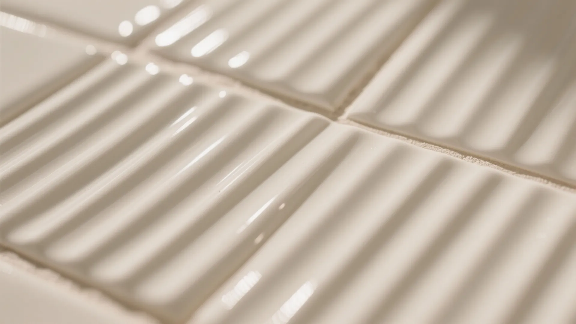 Close up view of white textured wall tiles with a vertical wavy pattern and grout