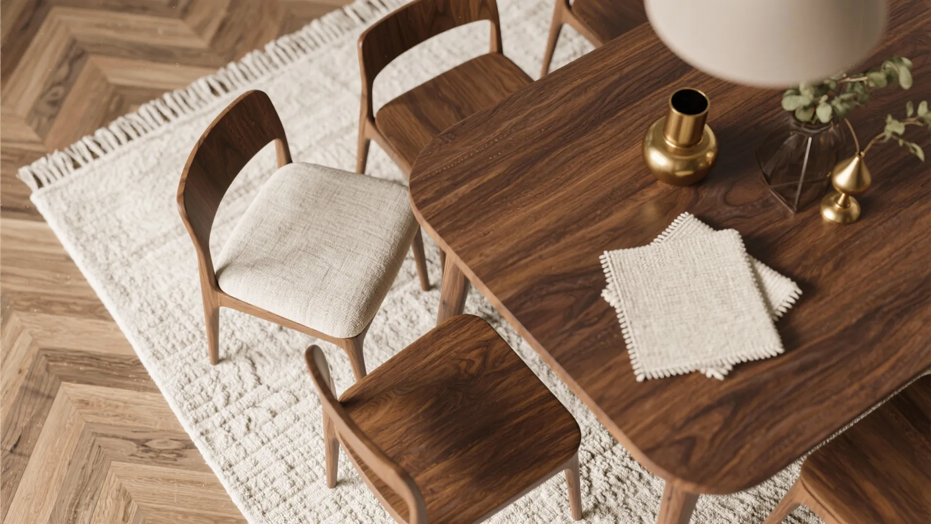 Modern wood dining table with chairs on white rug with herringbone floor and gold vase