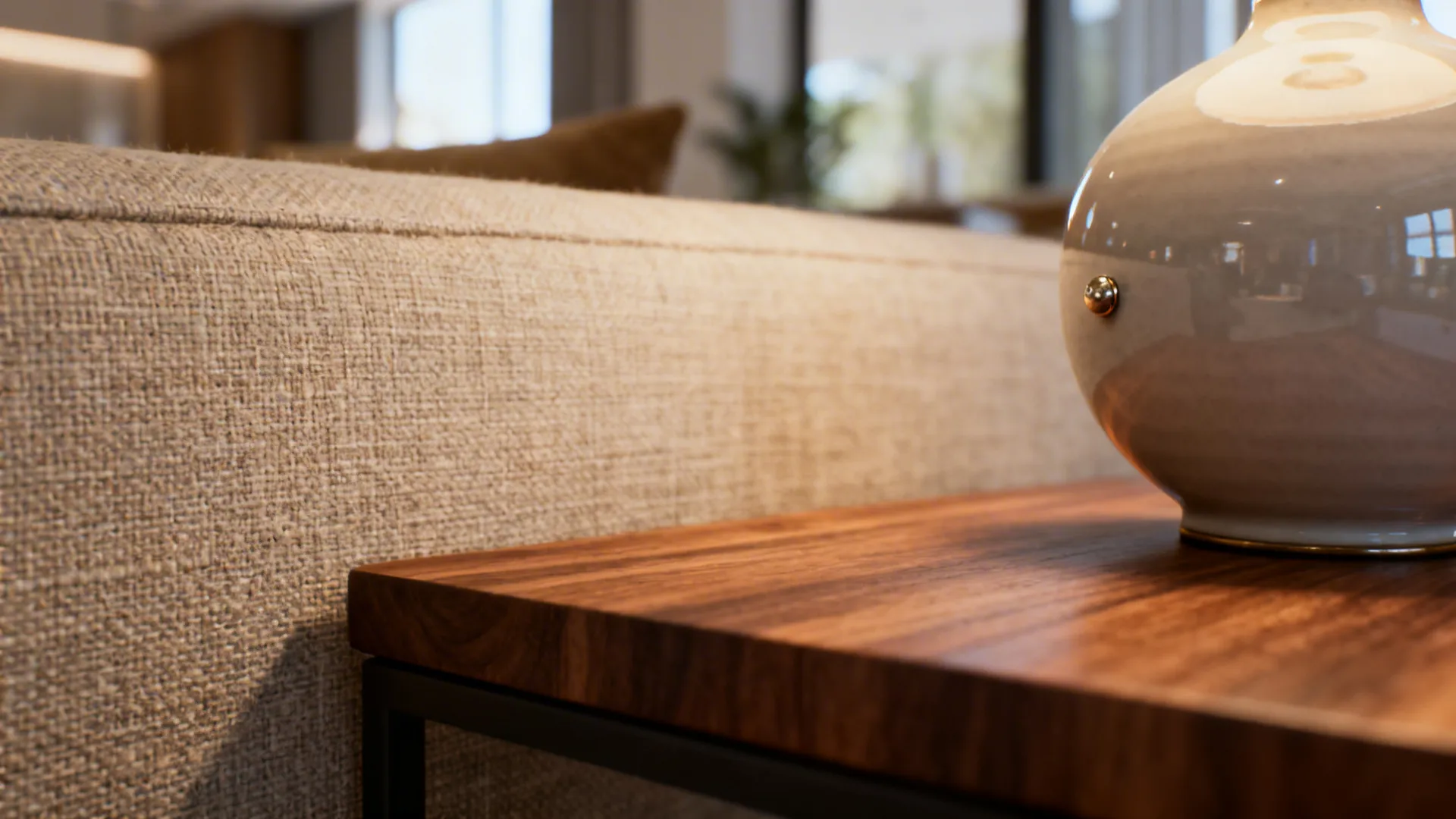 Close-up of linen sofa, matte wood table edge and glossy ceramic lamp showing varied textures.