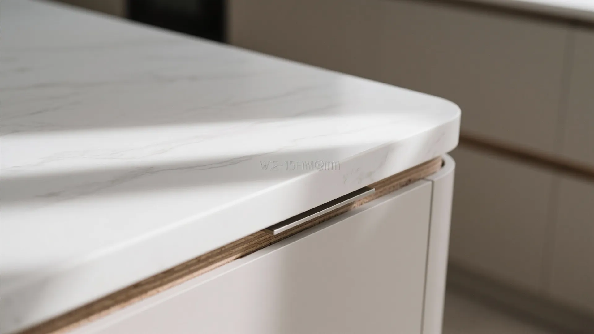 Close up of a white marble kitchen countertop with a curved corner and light wood detail