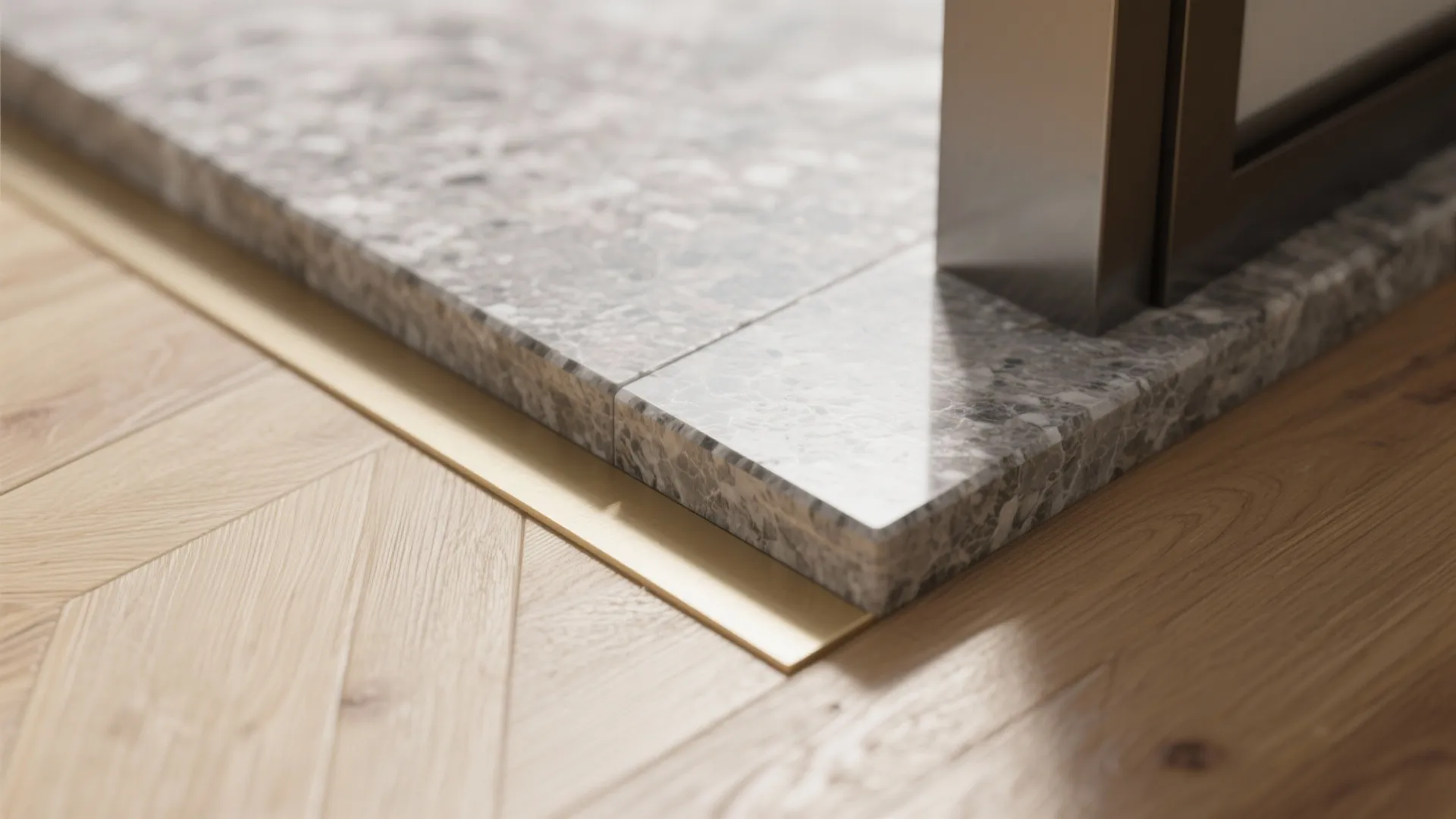 Close up of a marble floor meeting wood flooring with a thin gold metal floor strip