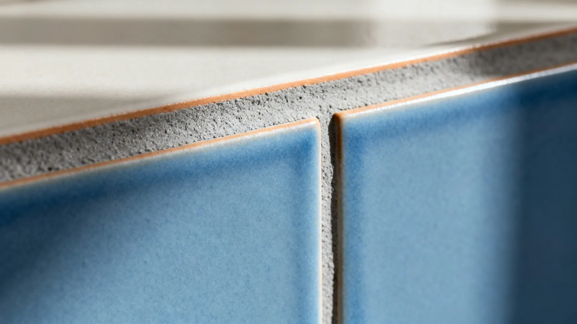 Macro of matte blue subway tile with warm grey grout highlighting texture.