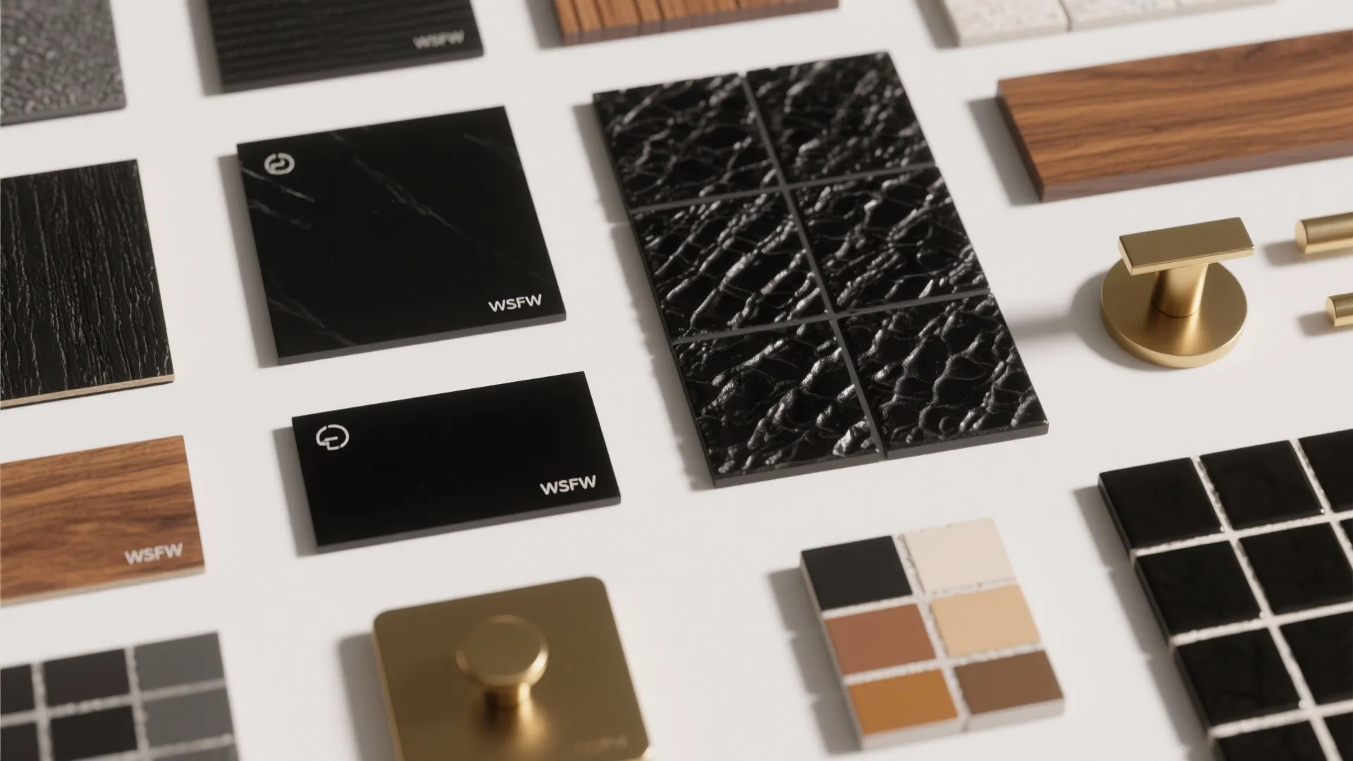 Flatlay of glossy, matte, and textured black tile samples with wood and brass accents and grout chips.