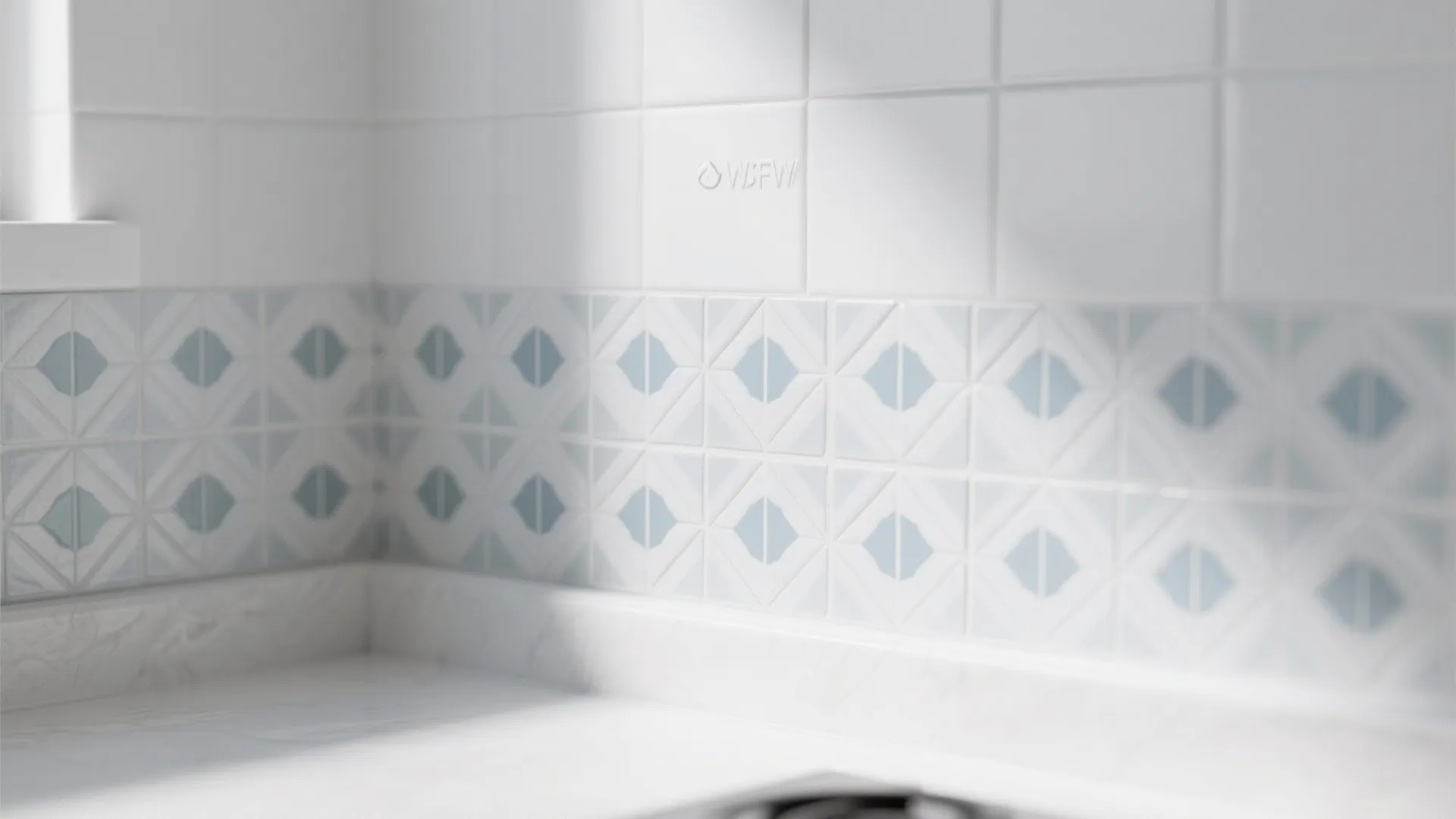 White wall tiles with decorative blue pattern border above a clean white kitchen counter top