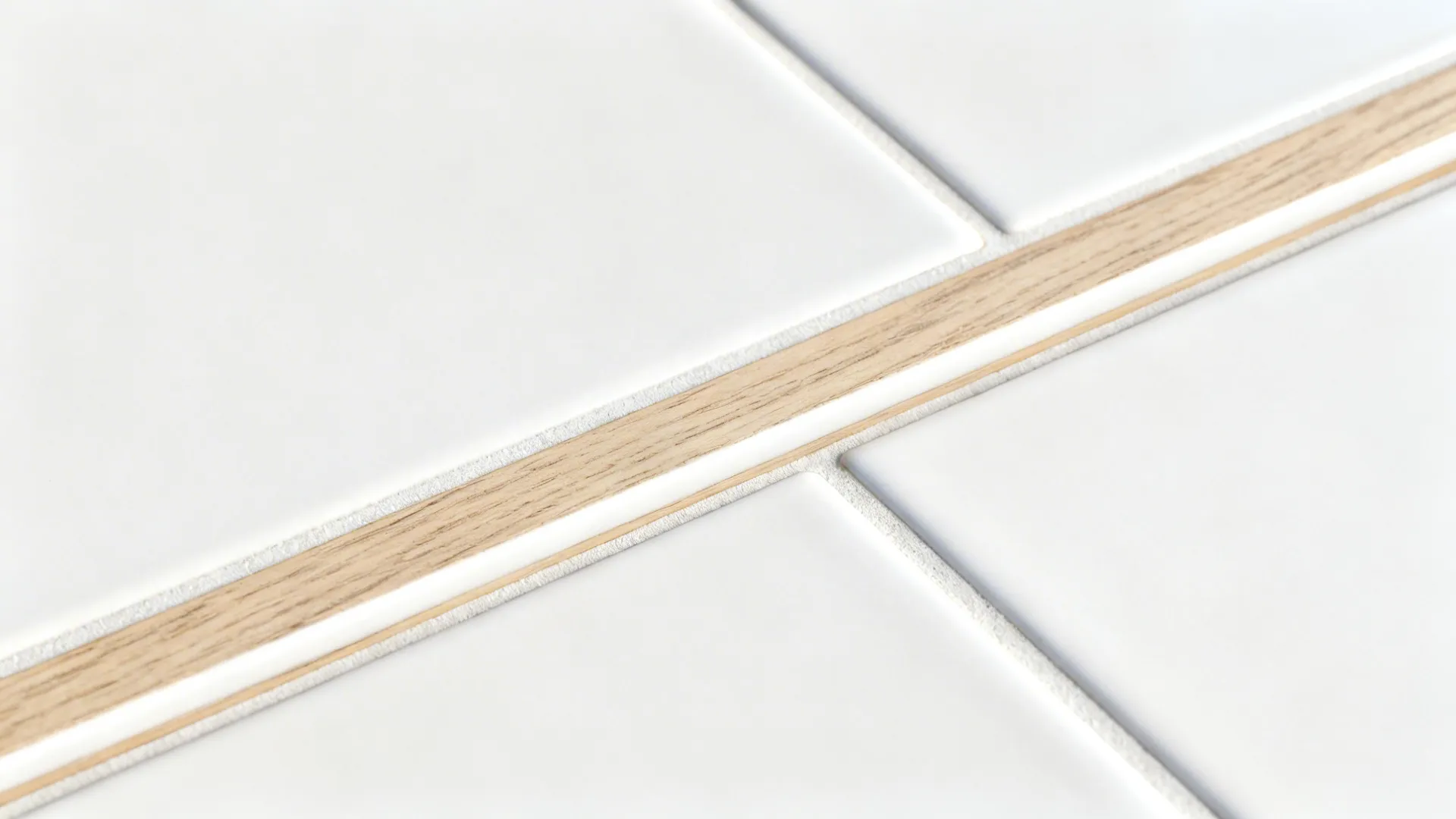 Macro of matte white tile meeting slim white-oak edge rail with clean grout line.