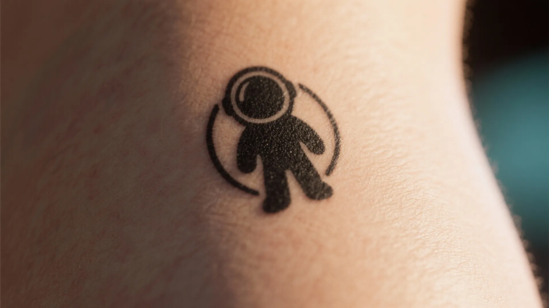 Simple black astronaut tattoo on skin showing a small space person figure inside thin circle