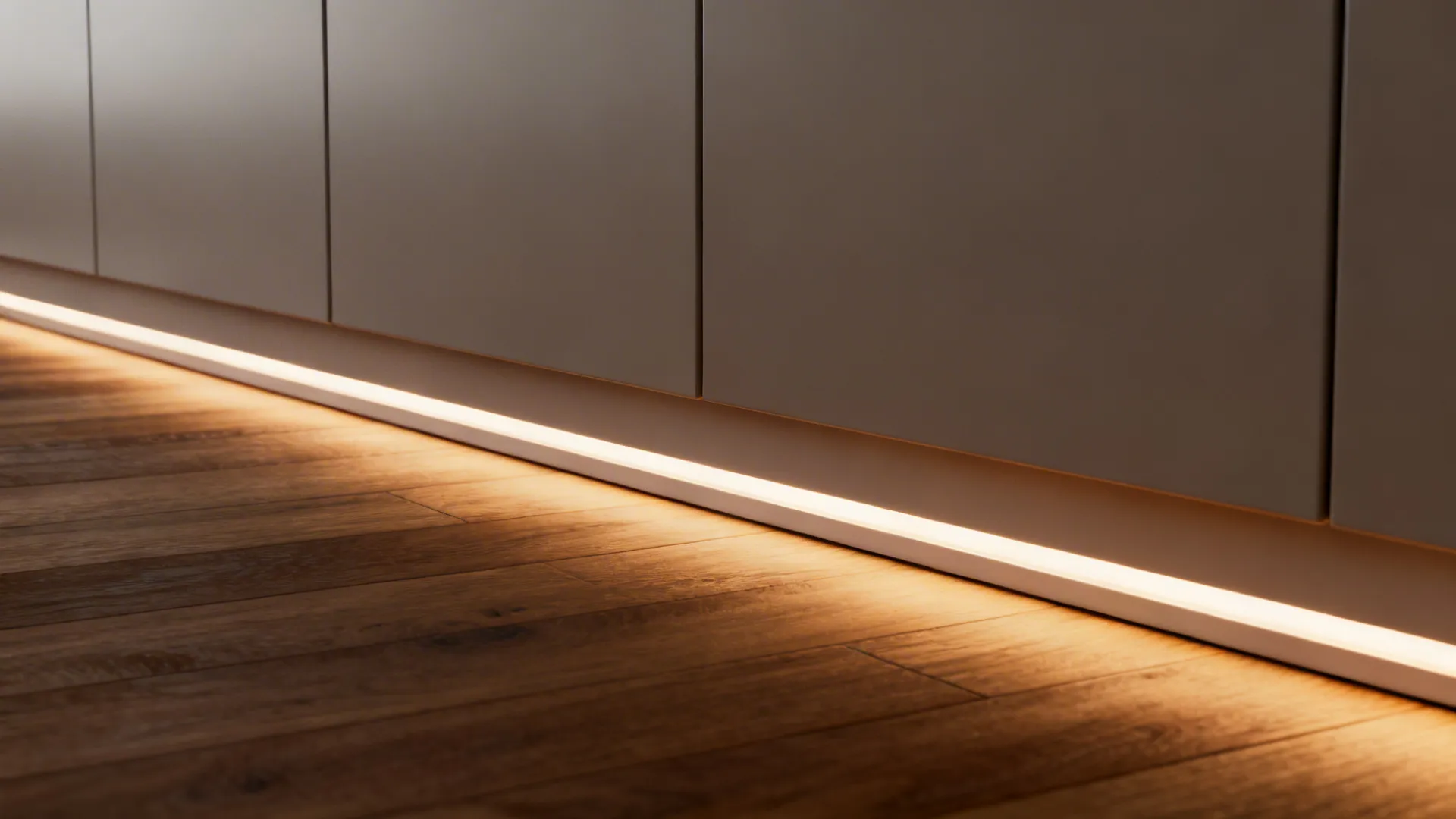 Macro of a diffused toe-kick LED channel casting a soft line on wood flooring.