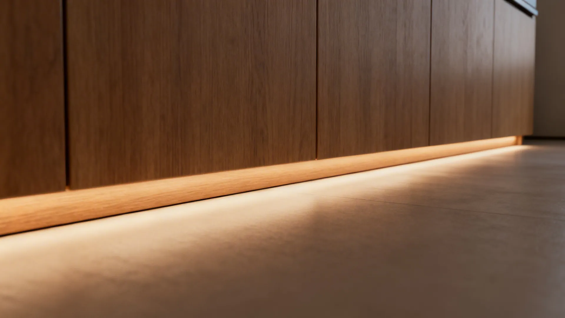 Macro of toe-kick LED glow along warm wood cabinets with soft floor wash.