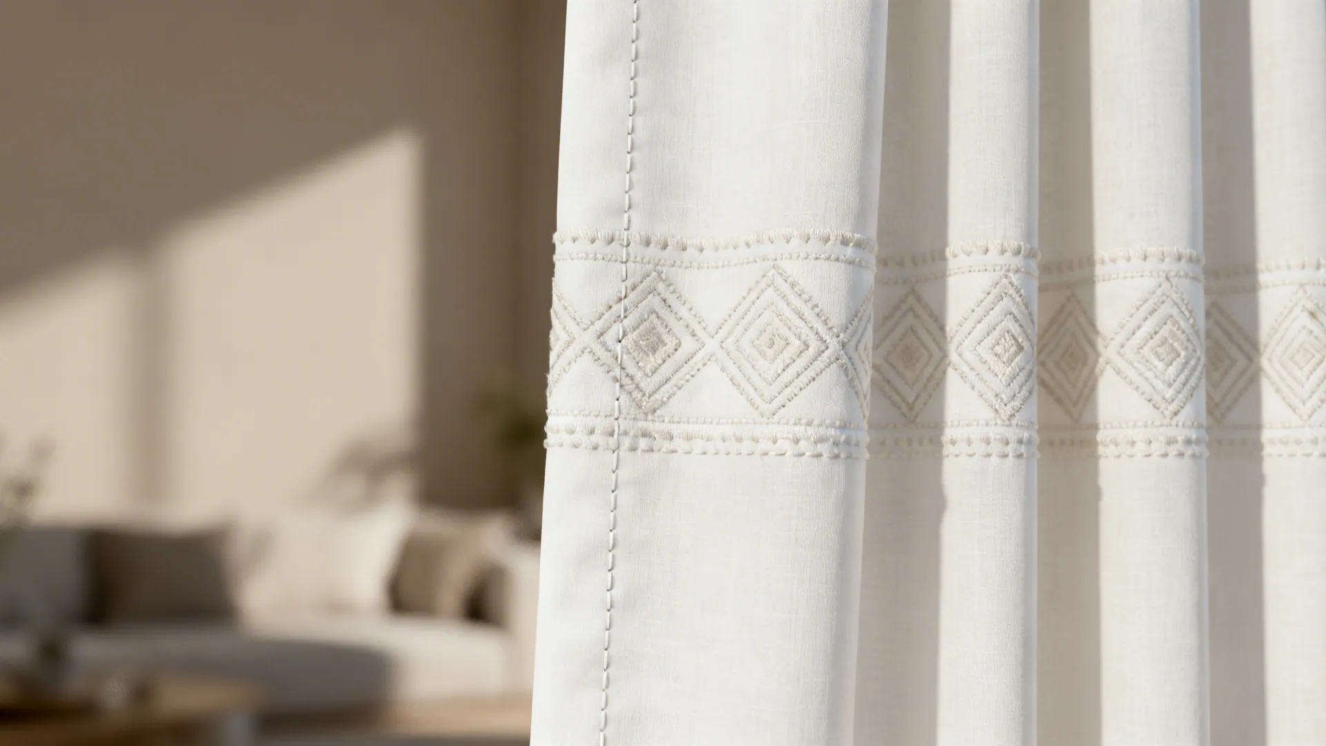 White curtain with subtle tone-on-tone embroidered geometric pattern in close-up.