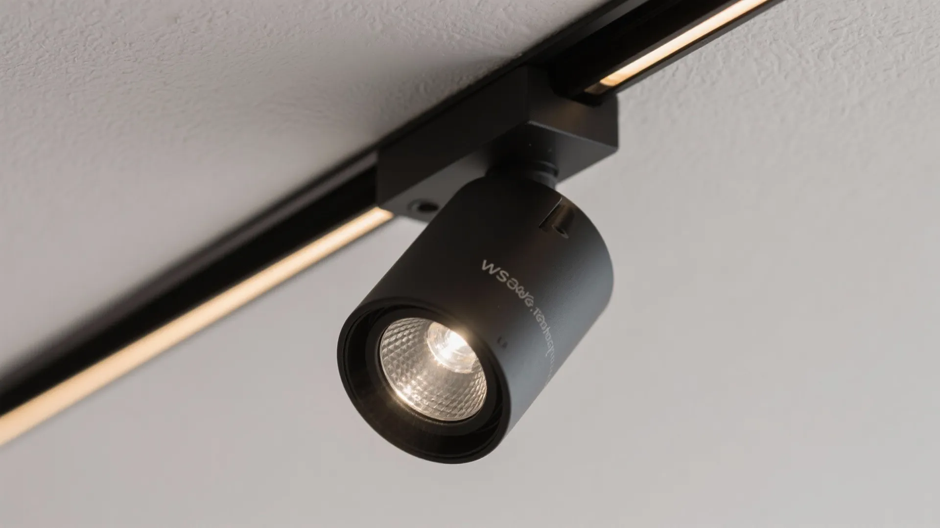 Close up of a single black adjustable track light fixture attached to a metal ceiling rail