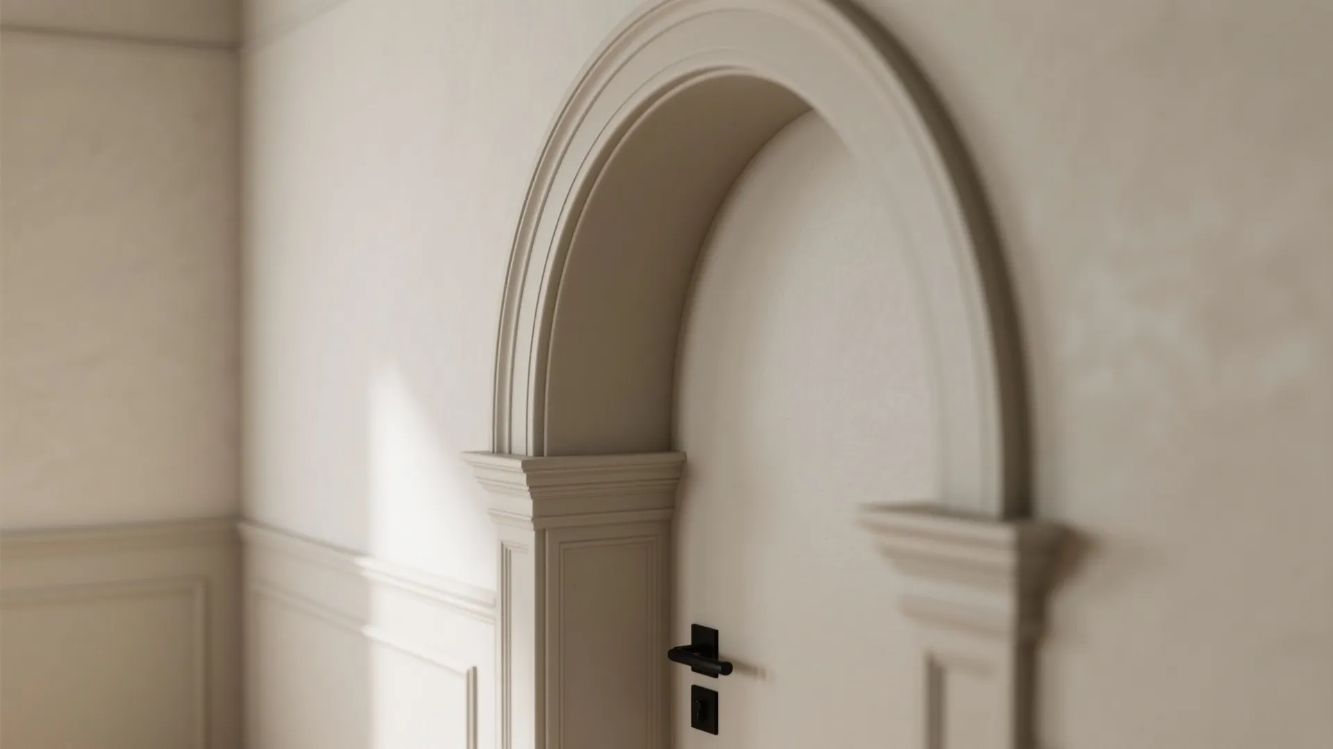 Cream colored wall with an arched doorway featuring decorative trim and simple white wall panel