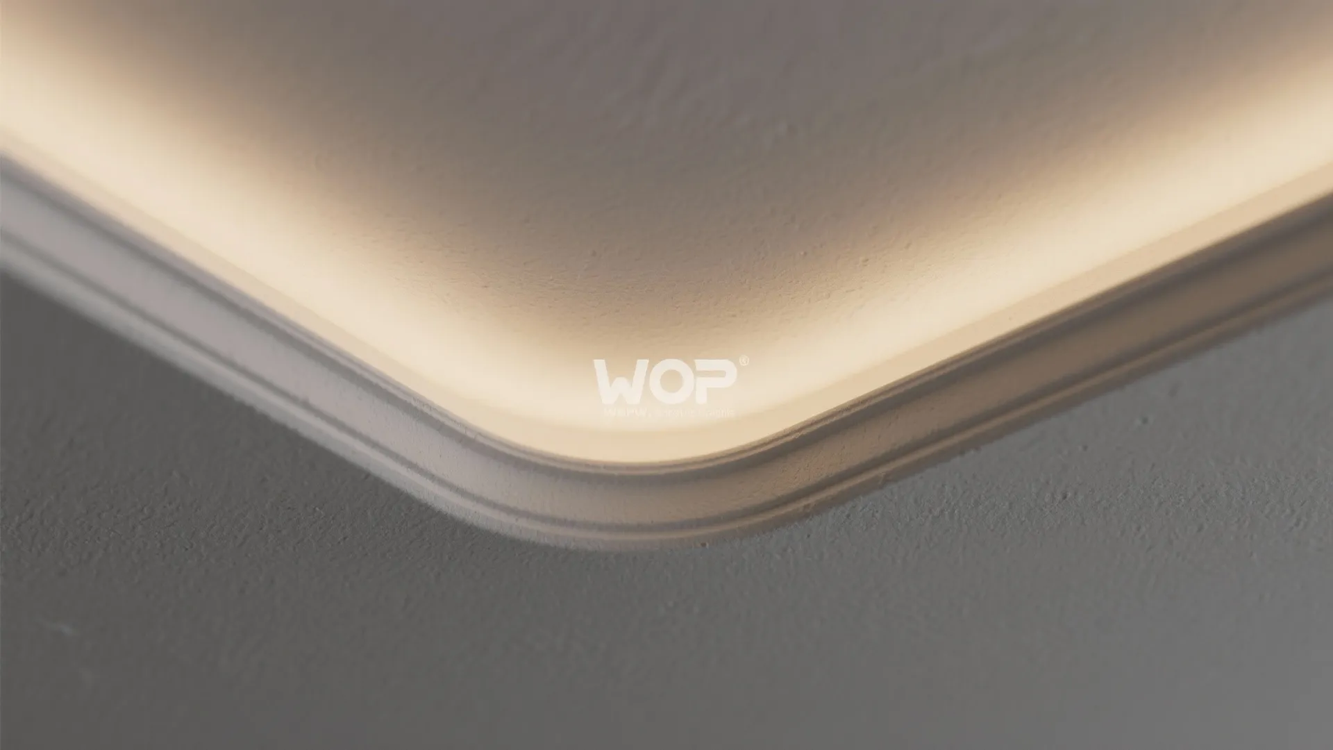 Close up view of a curved white ceiling wall panel with warm hidden light fixture glow