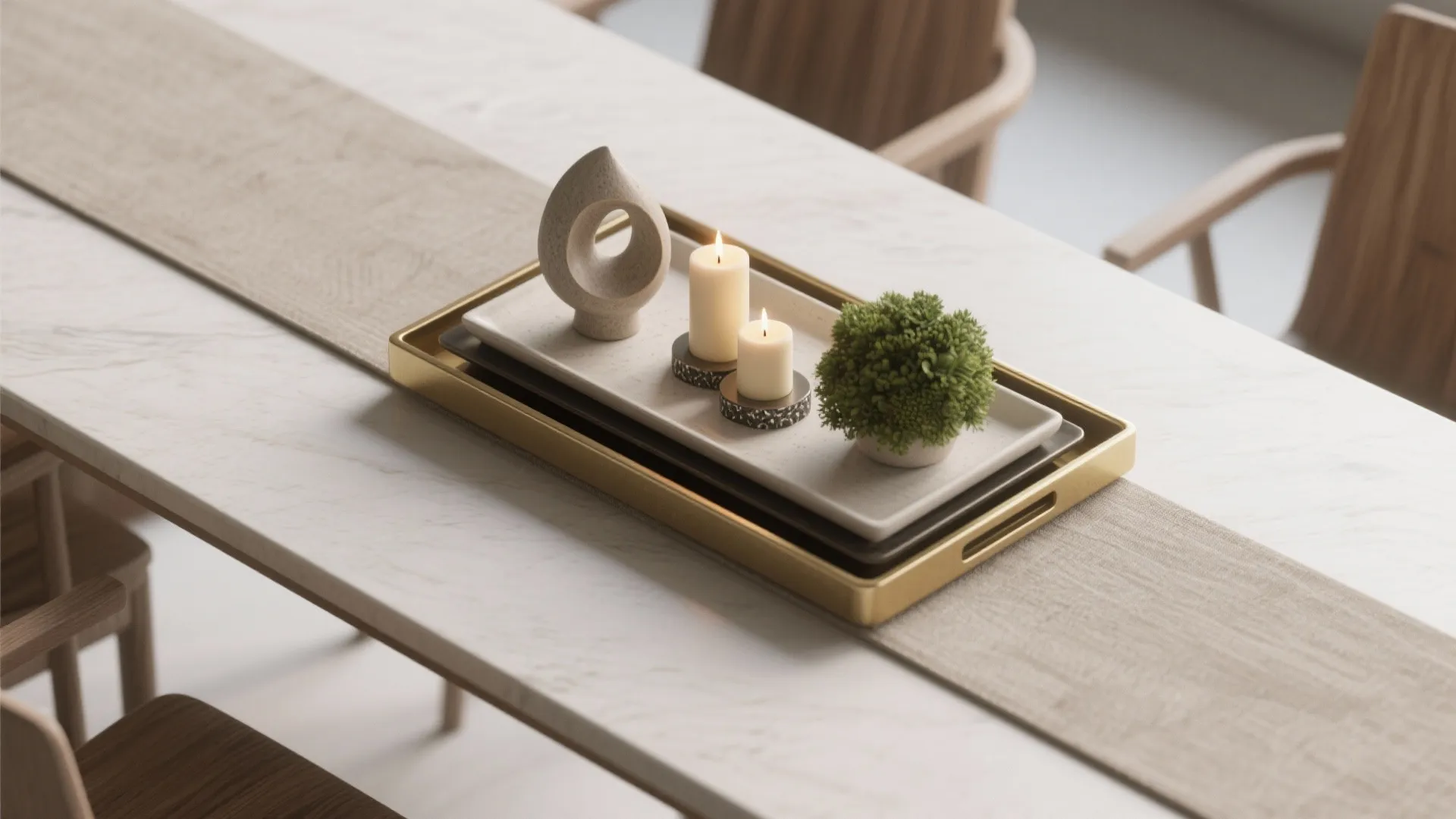 Top-down view of a layered tray arrangement with a sculptural object, grouped candles on a fireproof base, and a small greenery cluster on a rectangular table.