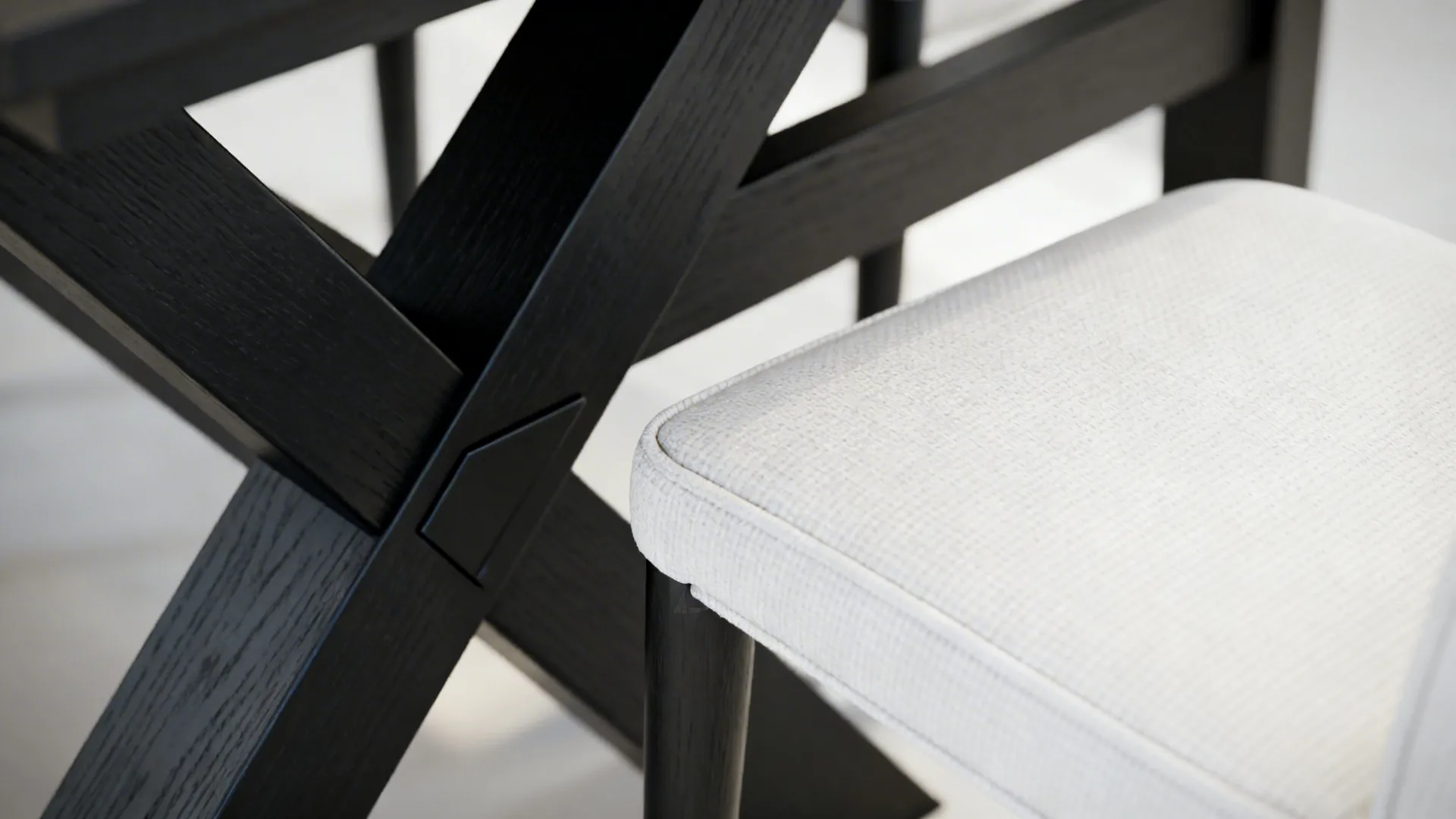 Close up of black wooden table legs next to a white fabric chair seat in sunlight
