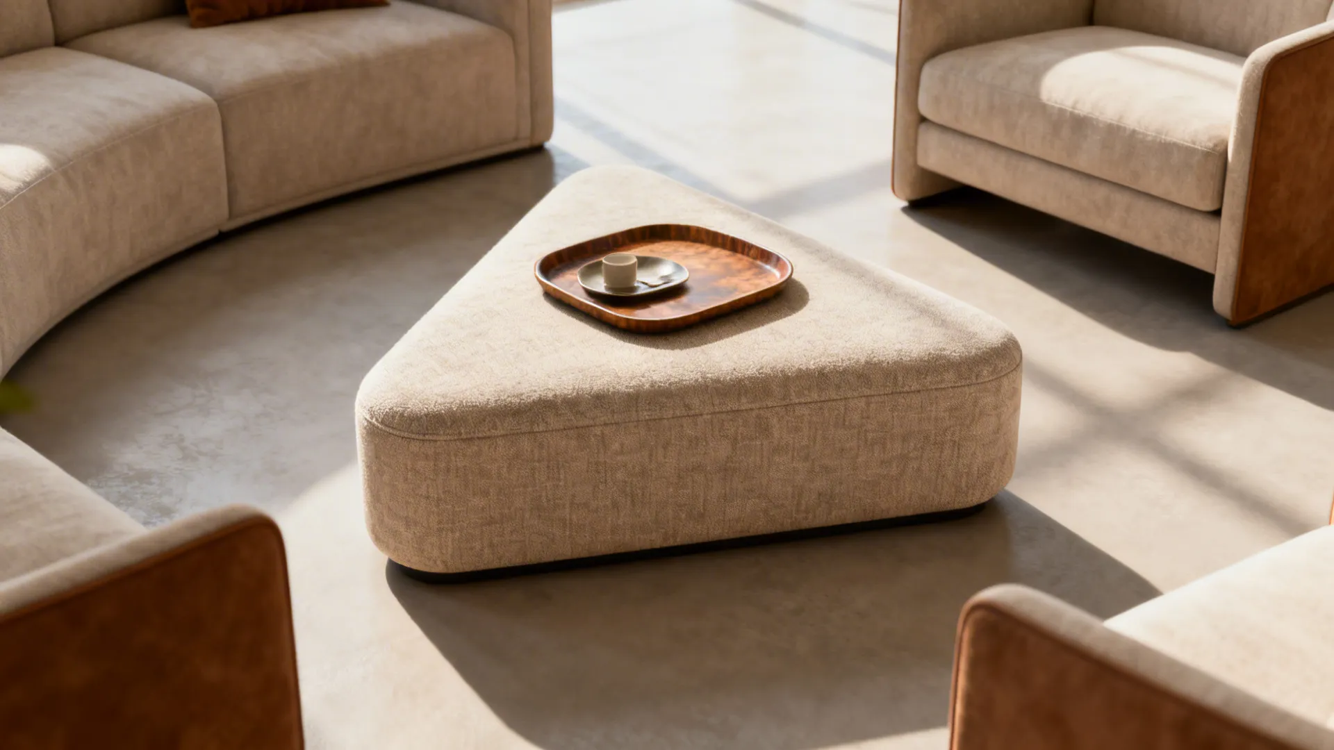 Triangular beige fabric footrest with wooden tray and cup placed in middle of two sofas