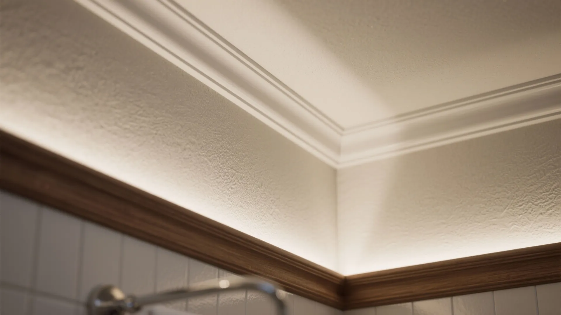 Close up of white ceiling trim with warm hidden light fixture and brown wood wall panel