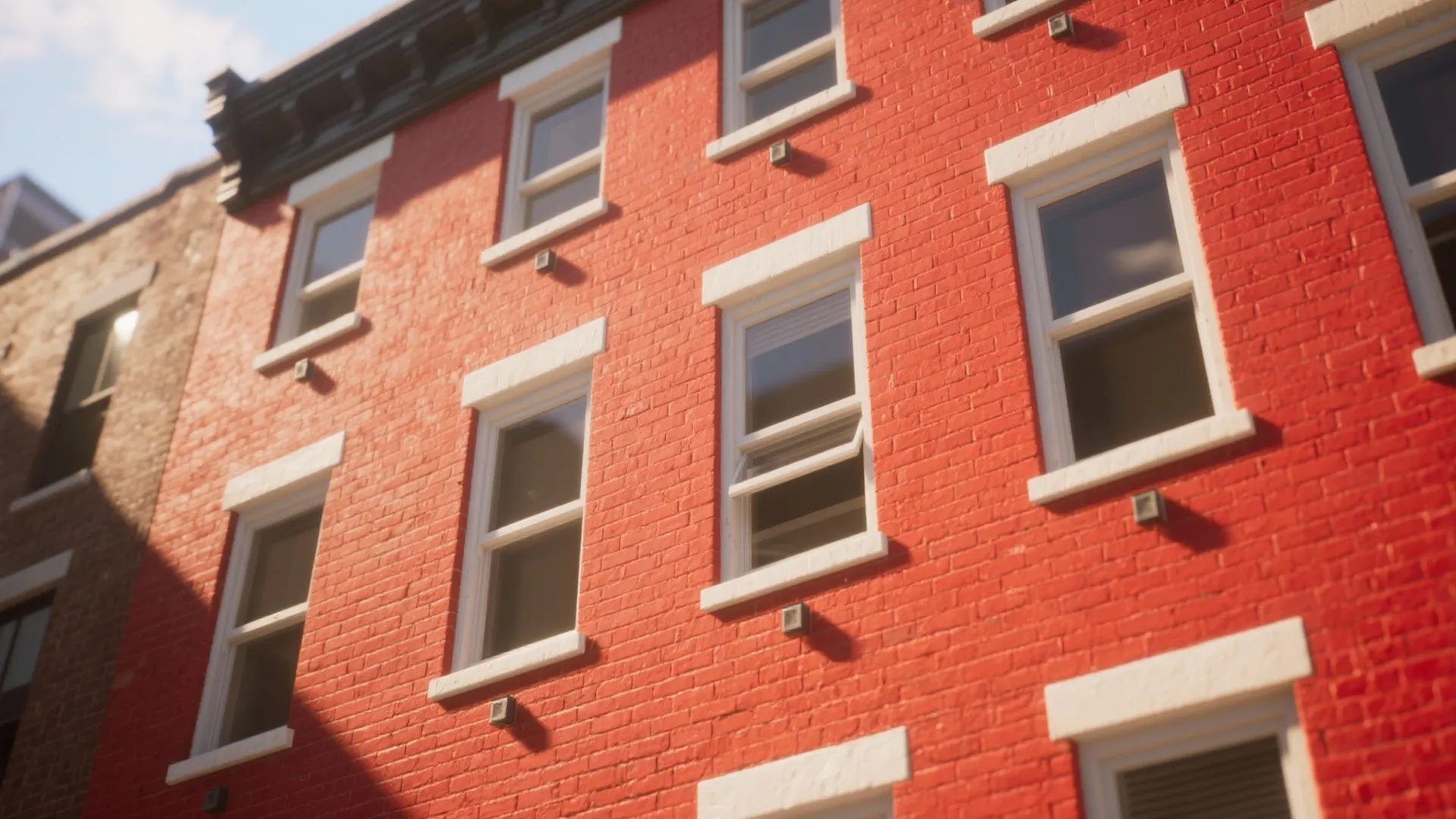 Exterior view of red brick building with multiple white windows under bright and sunny daylight