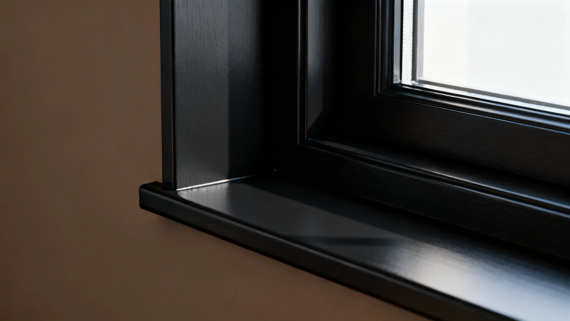 Close-up of deep charcoal trim against a warm taupe wall showing crisp paint edges and satin finish.
