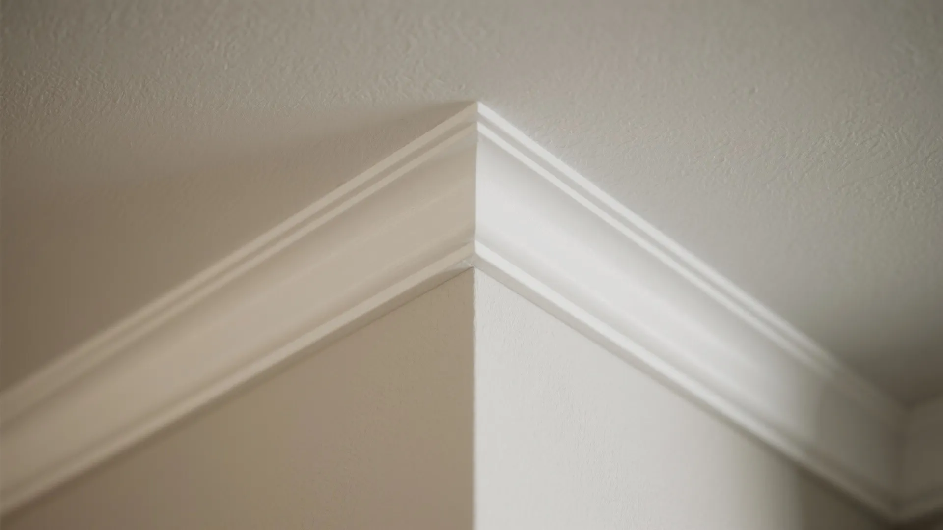 Close-up of white decorative wall panel trim meeting at the corner of a plain ceiling