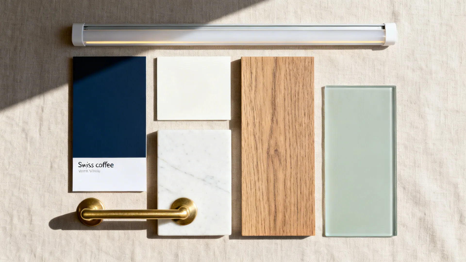 Top-down palette with navy laminate, warm off-white chip, ash veneer, quartz, brass, and glass samples.