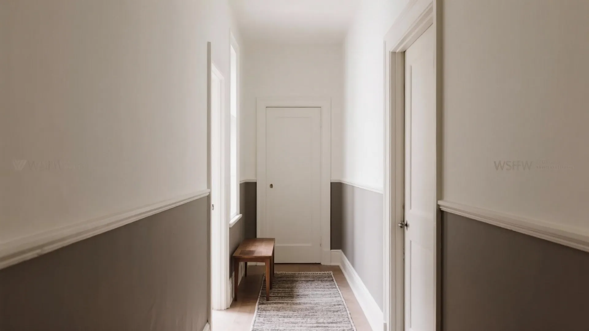Narrow hallway with white and grey wall panel wooden bench small rug and white doors