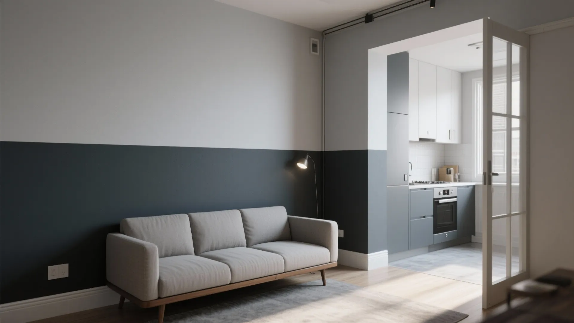 Living room with two-tone walls and grey sofa showing an open kitchen with white cabinets