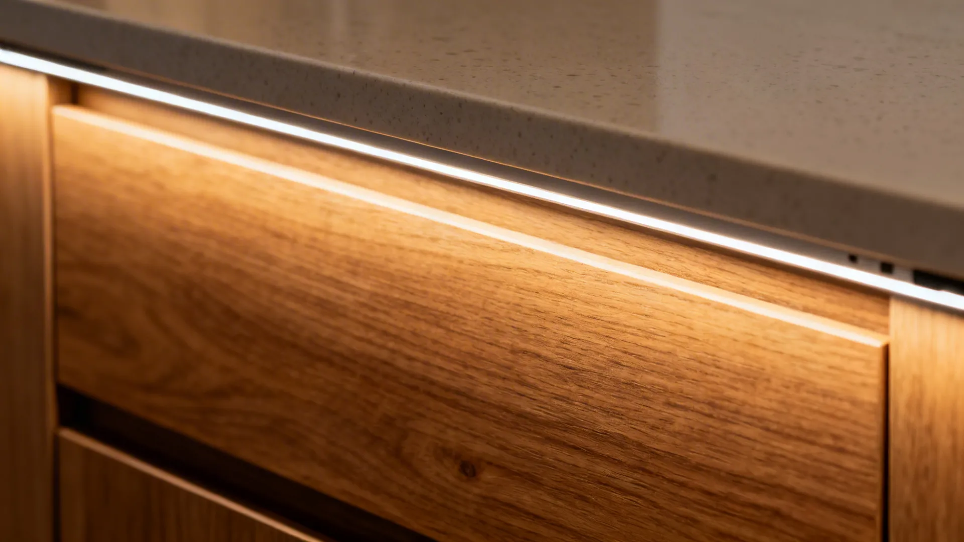 Close up of warm light fixture installed under a stone countertop on wooden kitchen storage cabinet
