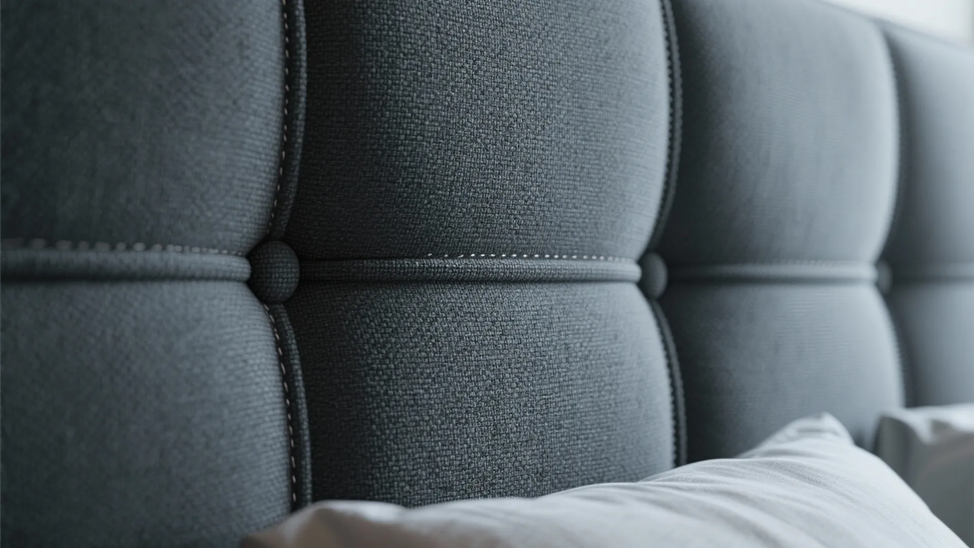 Close up of grey fabric wall panel with soft padding and decorative buttons in a bedroom