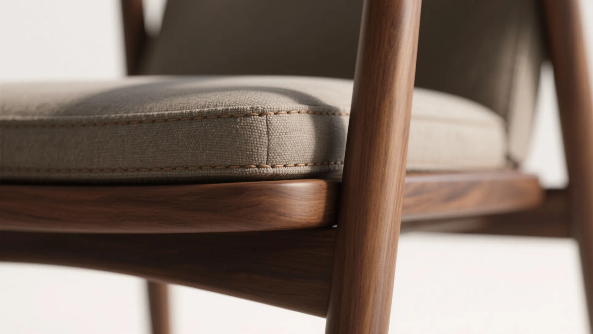 Close-up of walnut frame meeting an upholstered seat with fine stitching and matte finish.