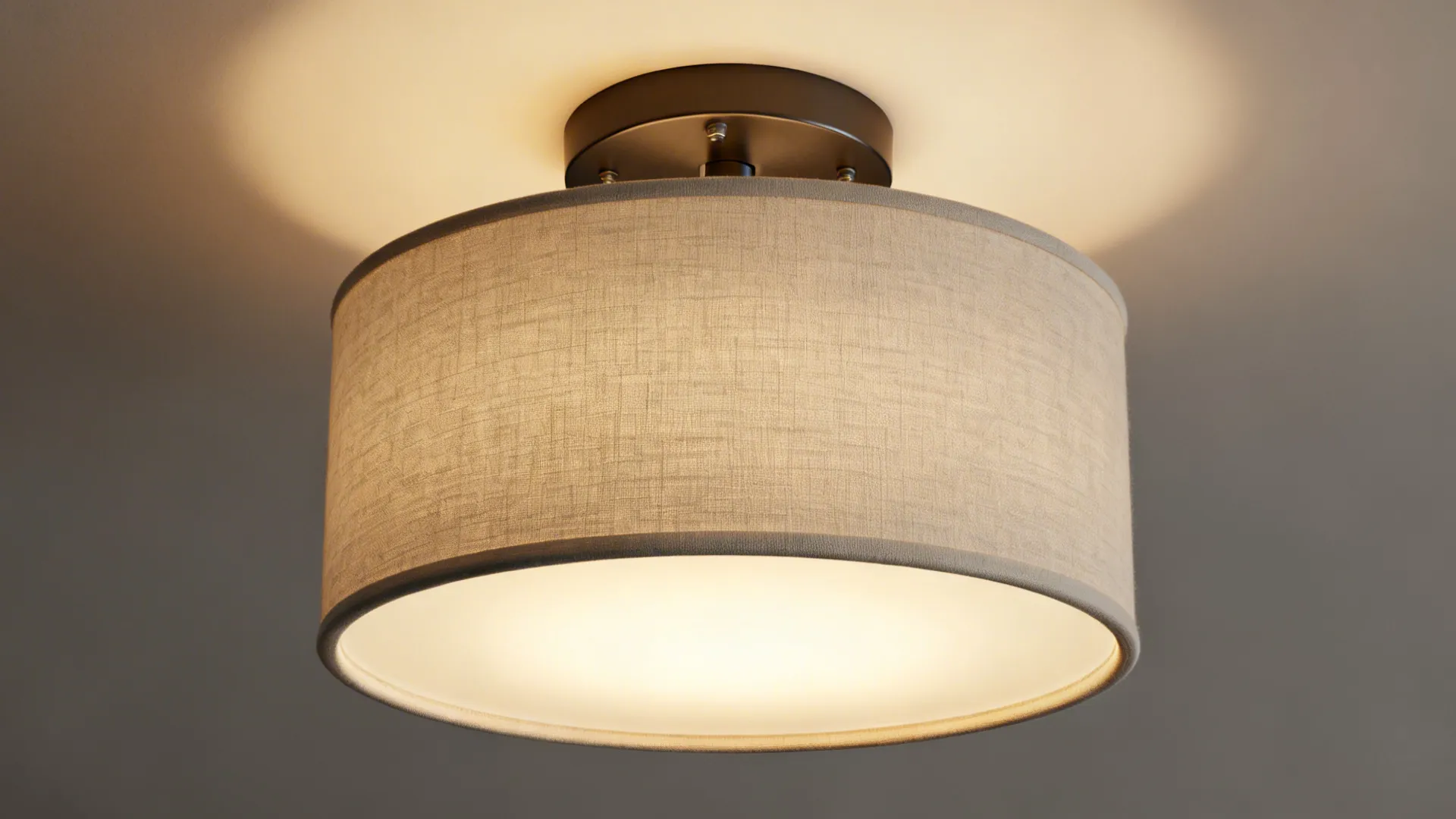Close up of round fabric ceiling light with dark metal base and warm yellow glow