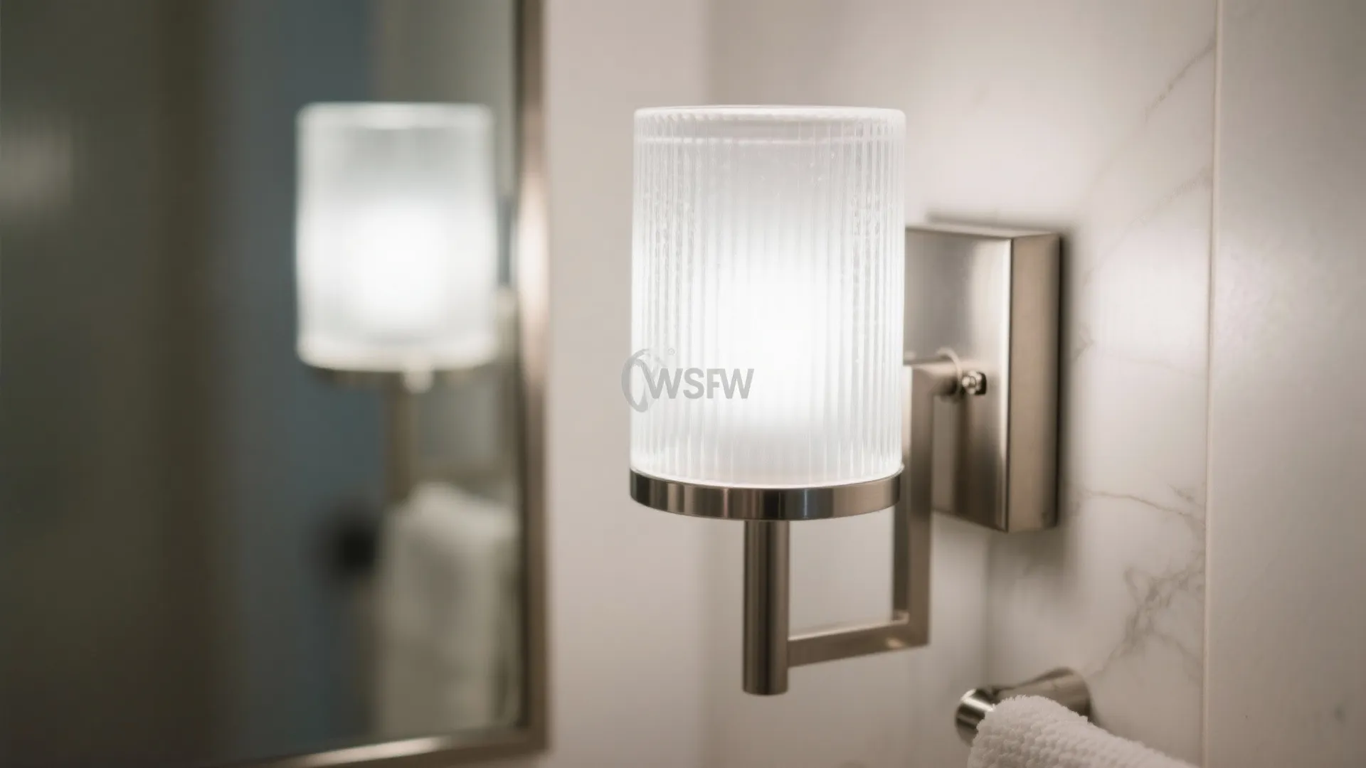 Close up of modern wall light with frosted glass shade mounted next to bathroom mirror