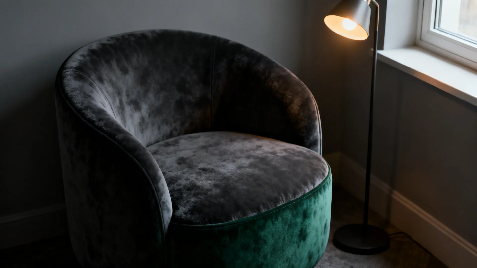 Round green velvet sofa placed near a window with a black floor light fixture beside it