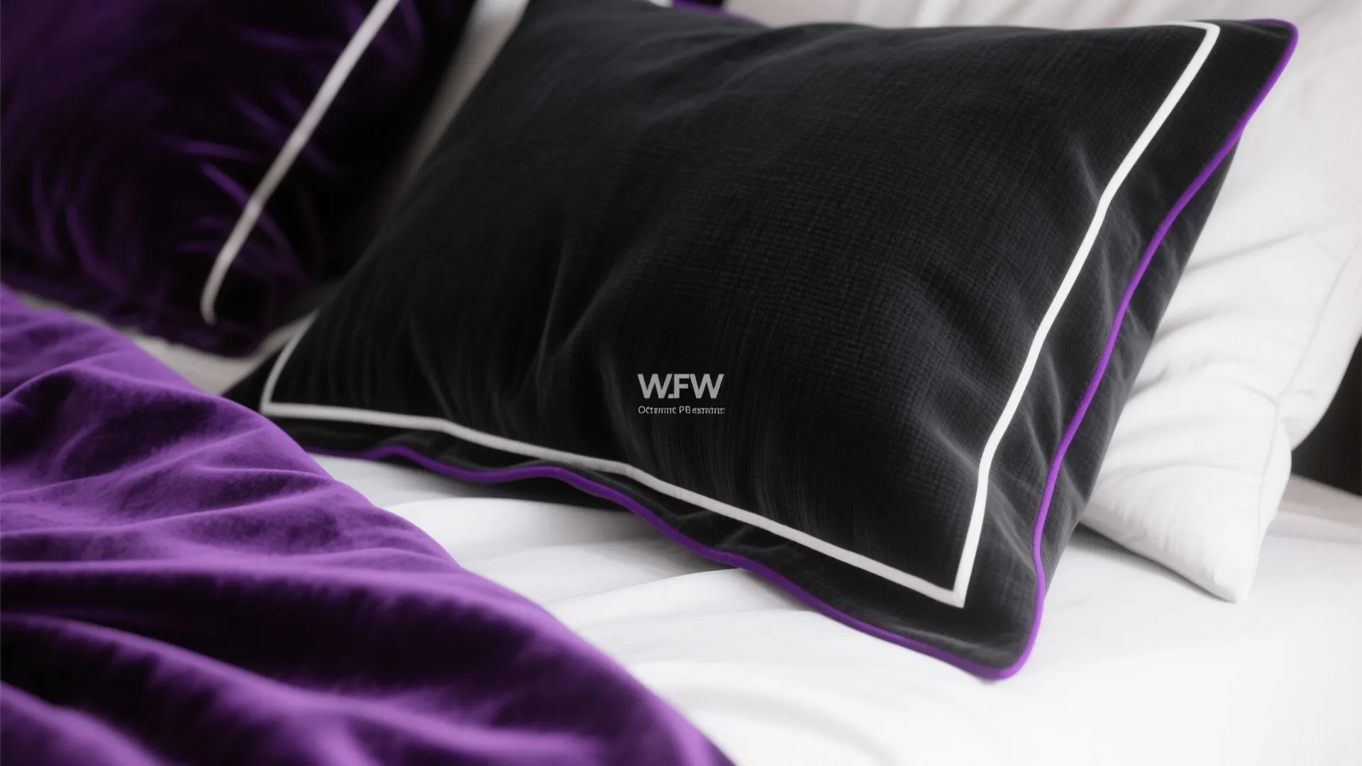 Close up of black and purple velvet pillows on a white bed with soft natural light