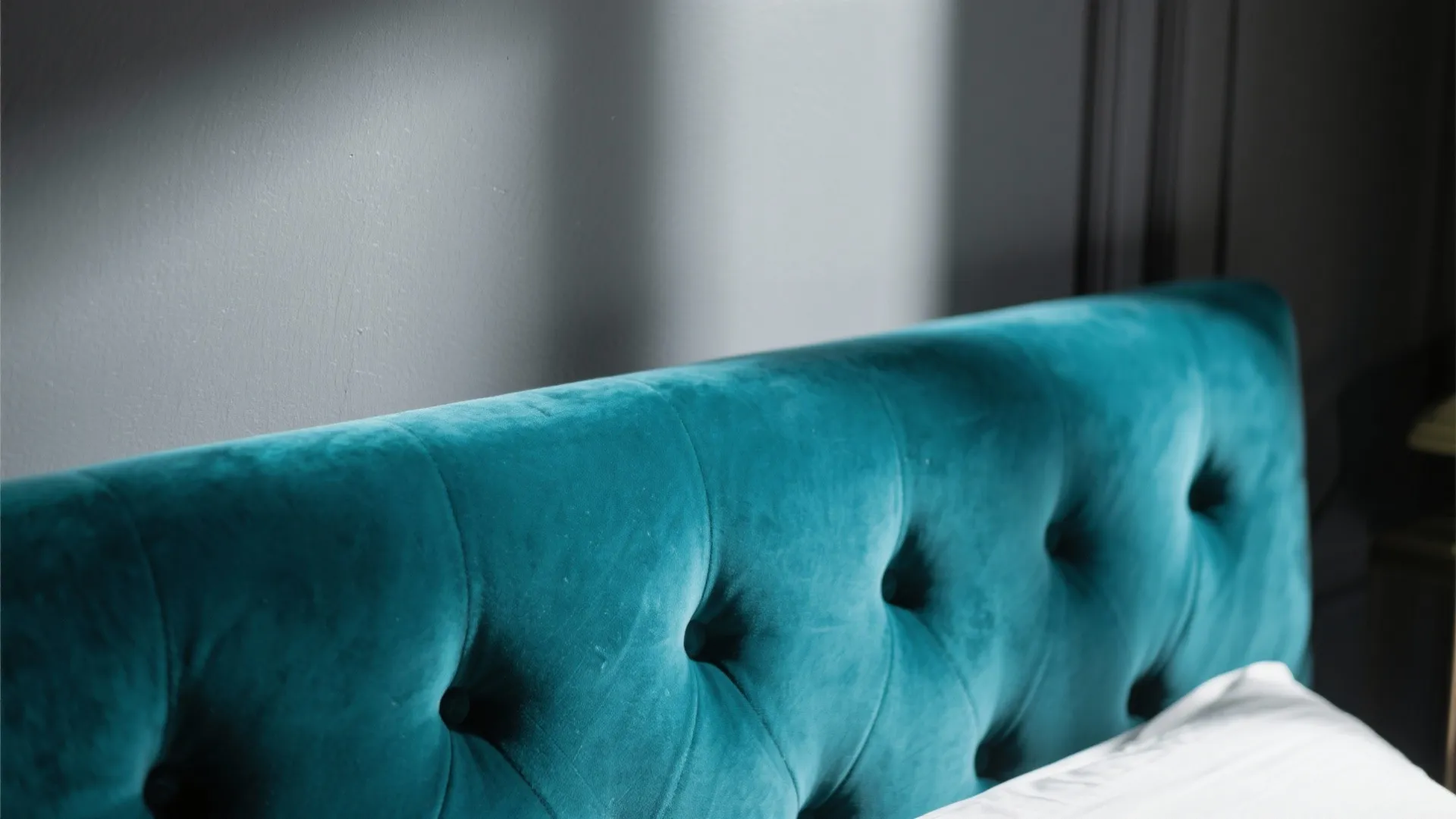 Plush velvet teal headboard with rich texture against charcoal wall
