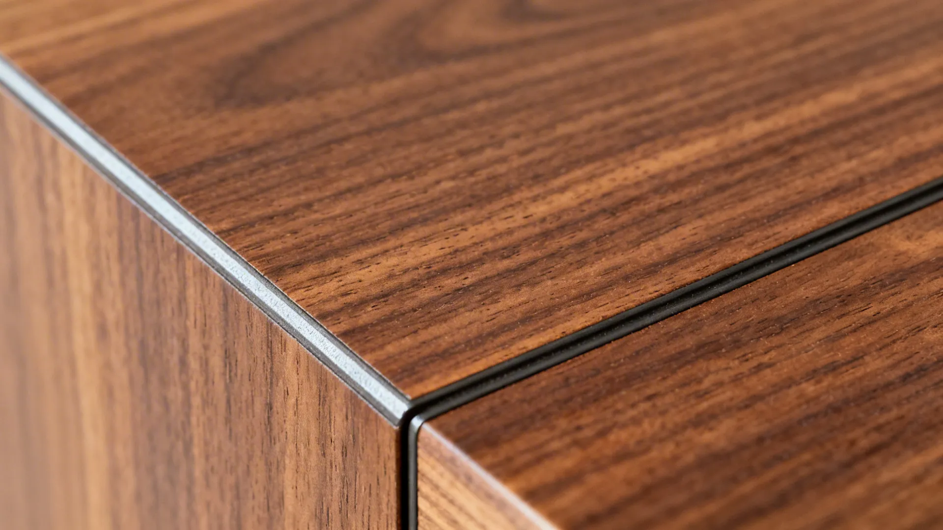 Macro of walnut veneer cabinet corner with seamless edge banding and fine grain.