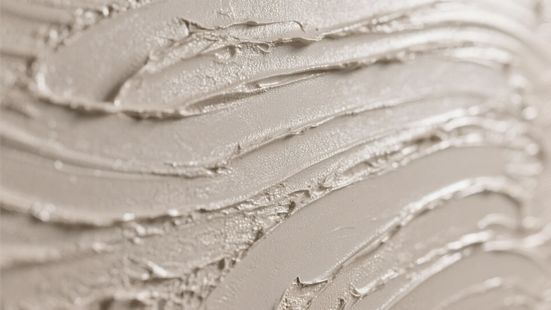 Close up shot of beige textured wall paint with rough wavy strokes and natural lighting