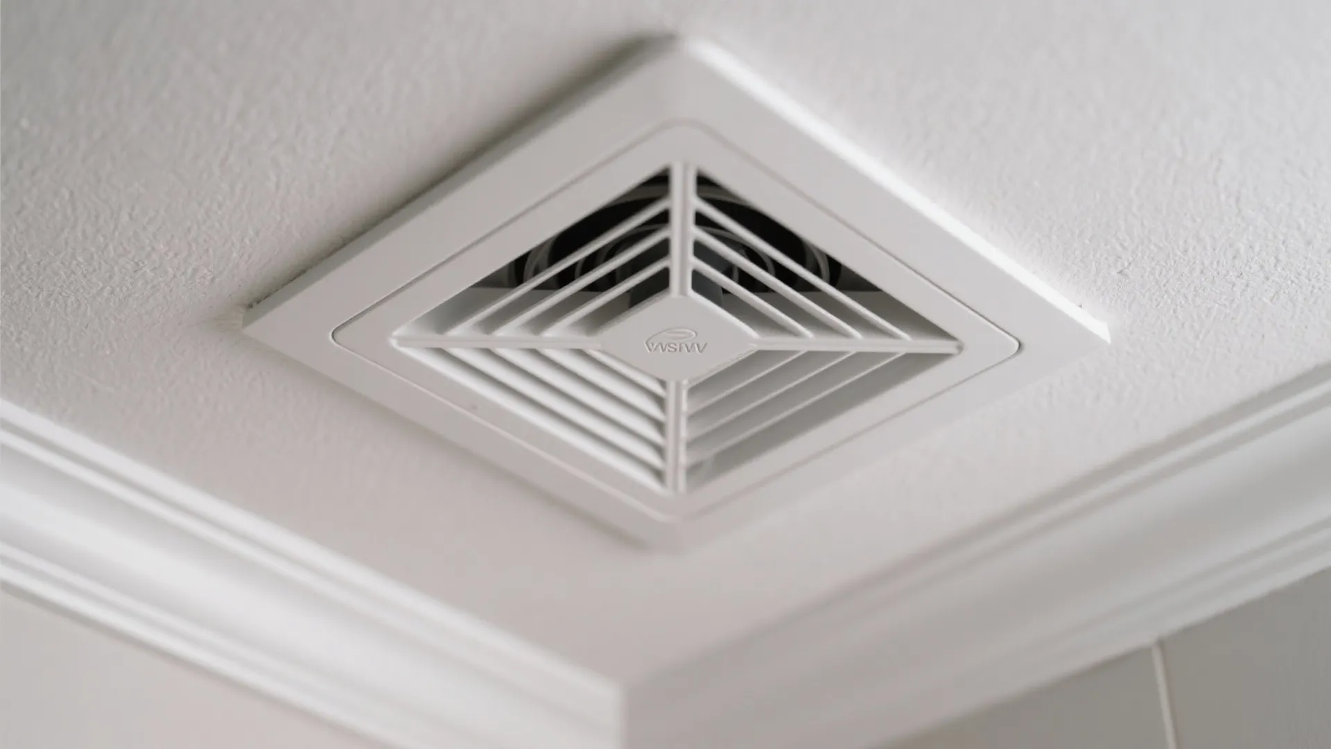 White square ventilation fan installed on a white ceiling for bathroom air flow and cooling