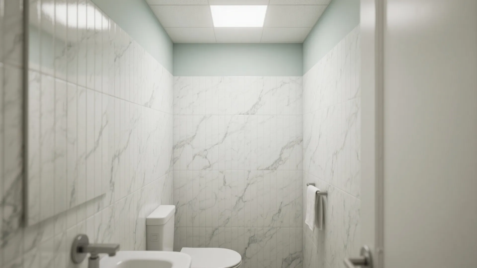 Modern bathroom with white marble wall tiles, white toilet, sink, and bright square ceiling light