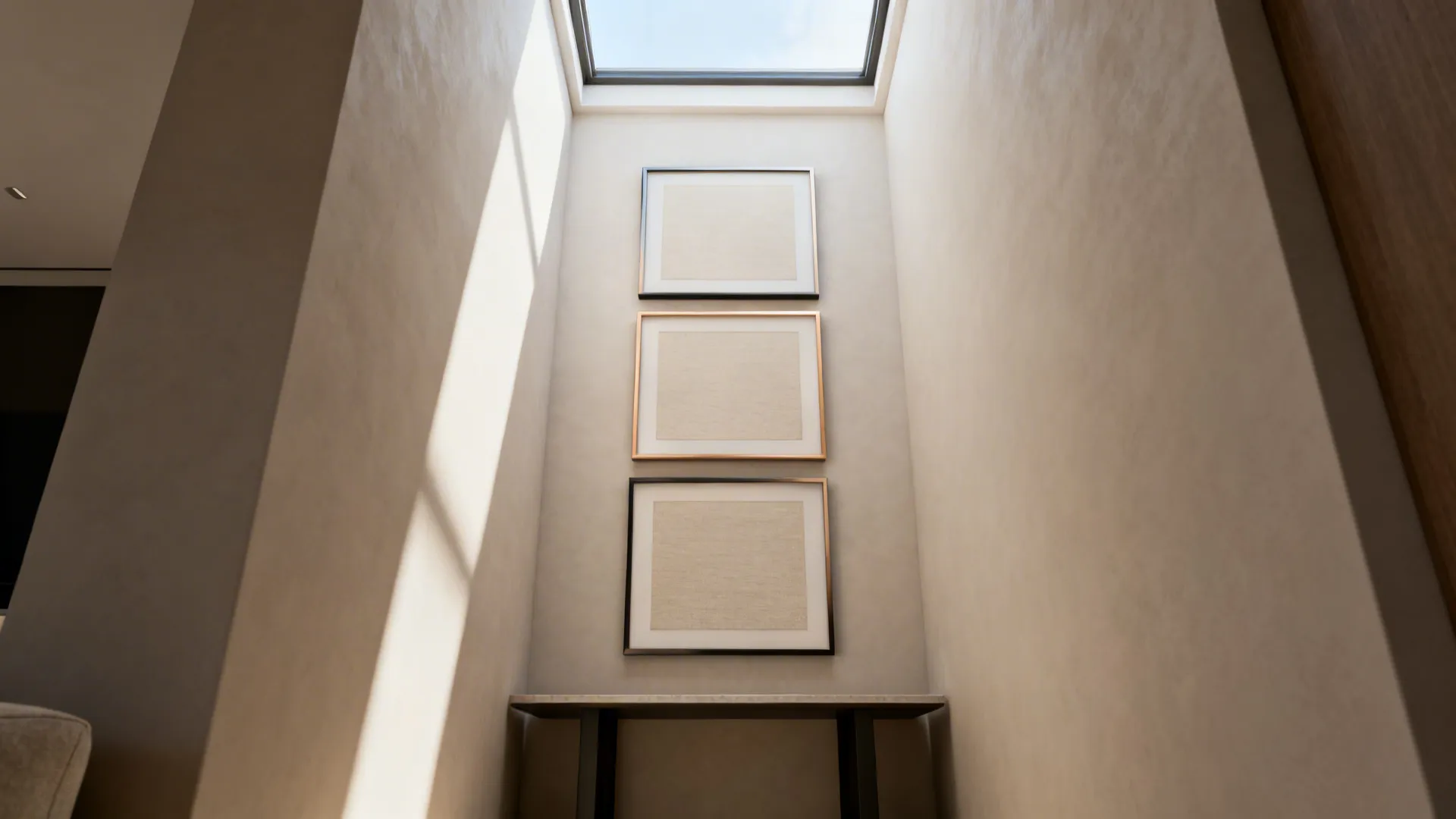 Narrow hallway with three framed pictures stacked vertically under a bright roof window and table